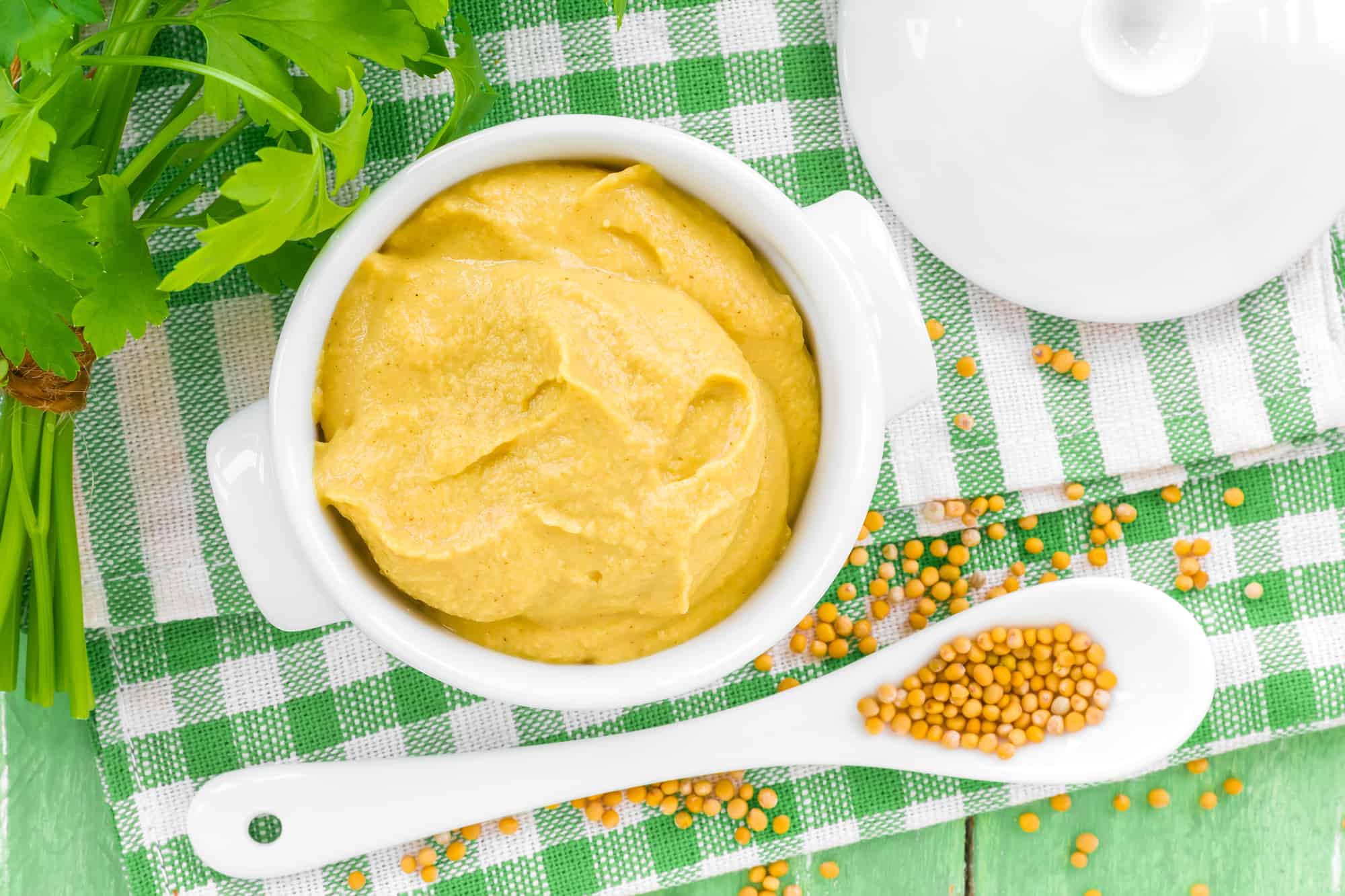 mustard with mustard seeds on a green table cloth