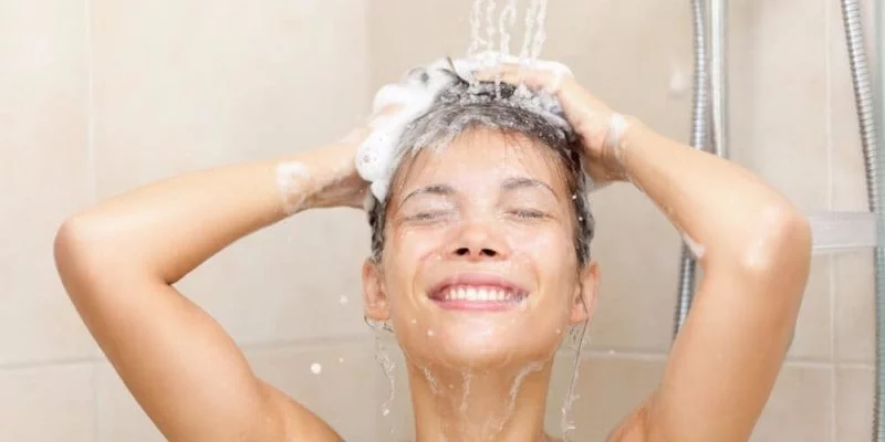 photo of beautiful woman showering washing hair with splashing water