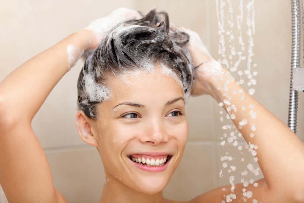 photo of smiling woman shampooing her hair