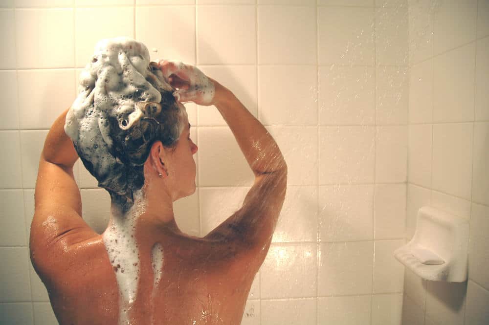photo of woman shampooing hair in shower