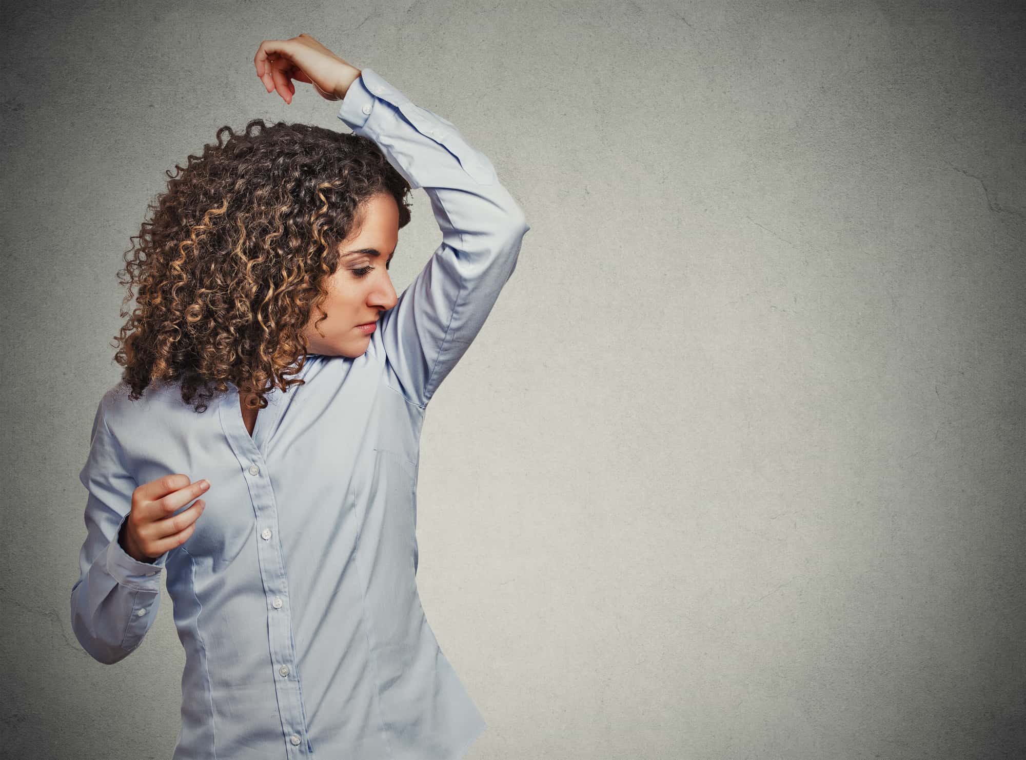 Woman sniffing her armpits and she needs deodorant