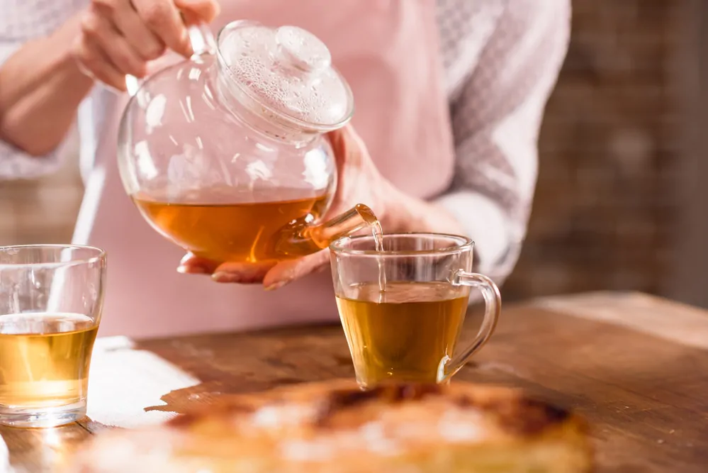 woman pouring tea from glass tea pot