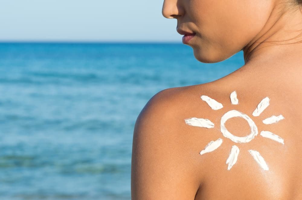 Woman With Suntan Lotion At The Beach In Form Of The Sun