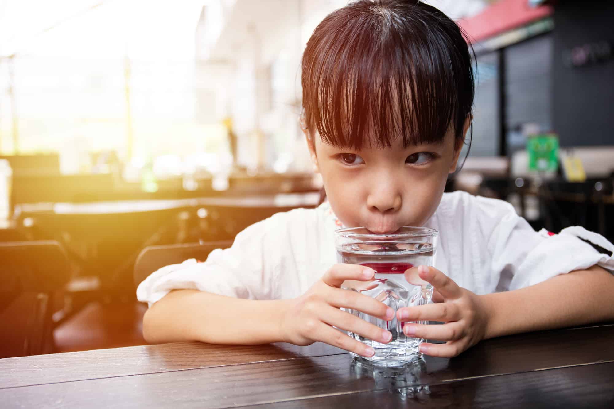 girl drinking water in outdoor cafe