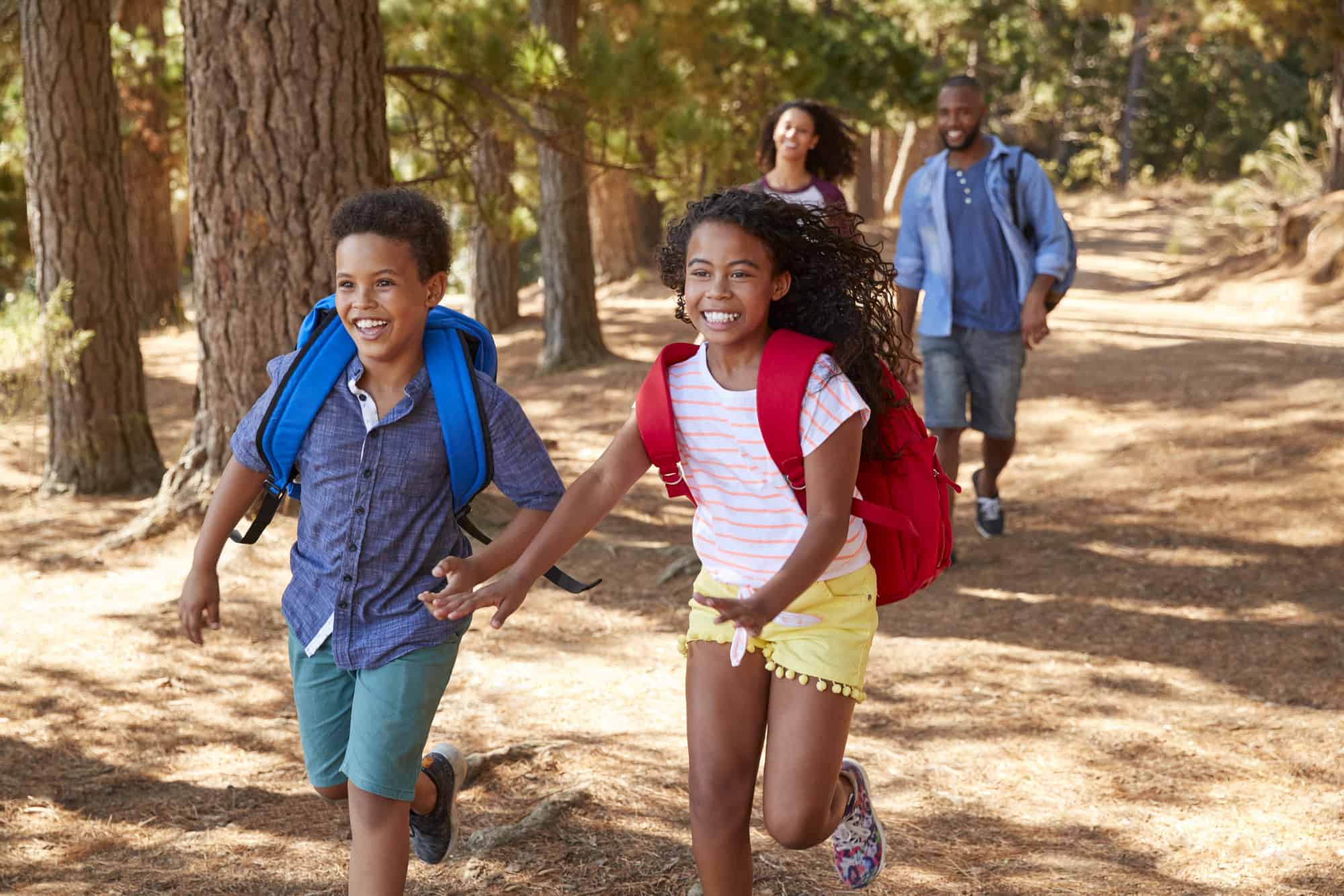 Children Running Ahead Of Parents On Family Hiking Adventure