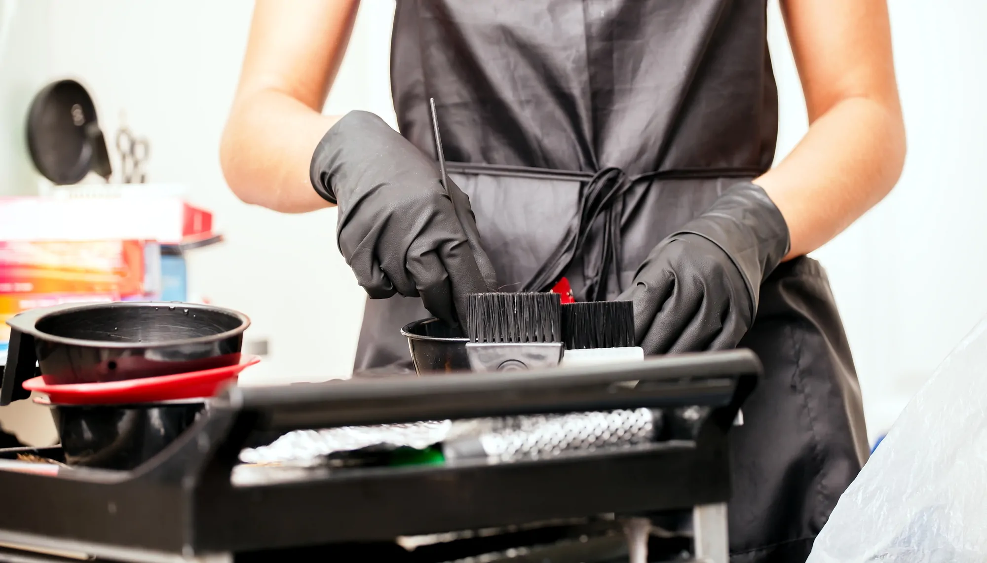 girl in black gloves hairdresser mixes hair dye