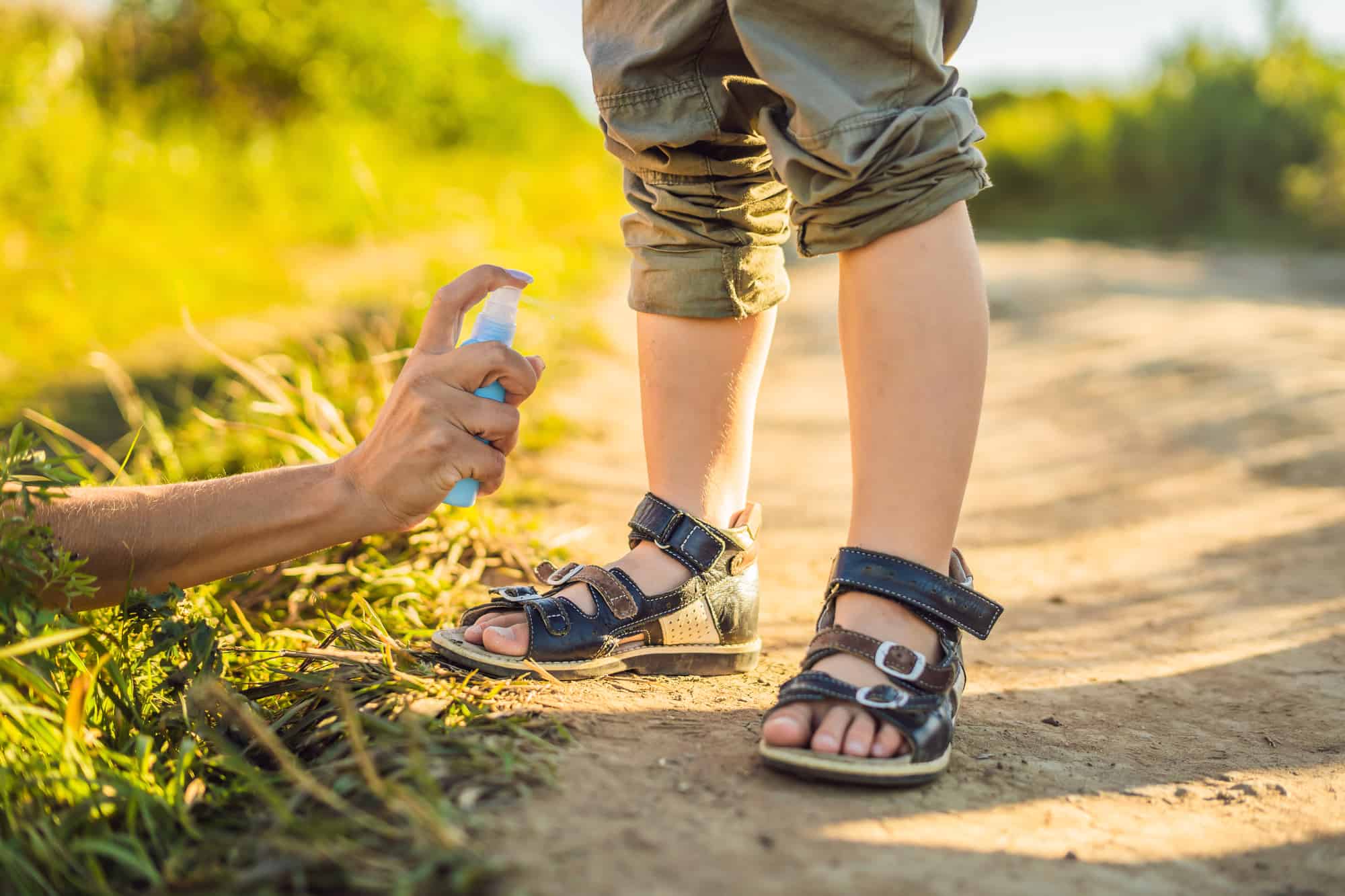 Mom and son use mosquito spray.Spraying insect repellent on skin outdoor