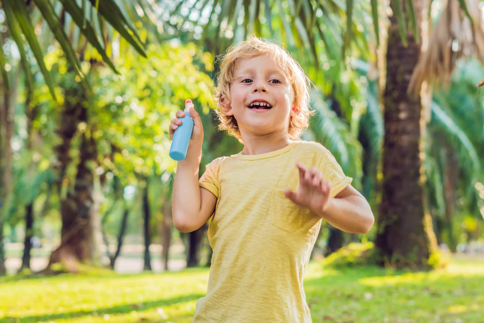 Boy spraying insect repellents on skin in the park