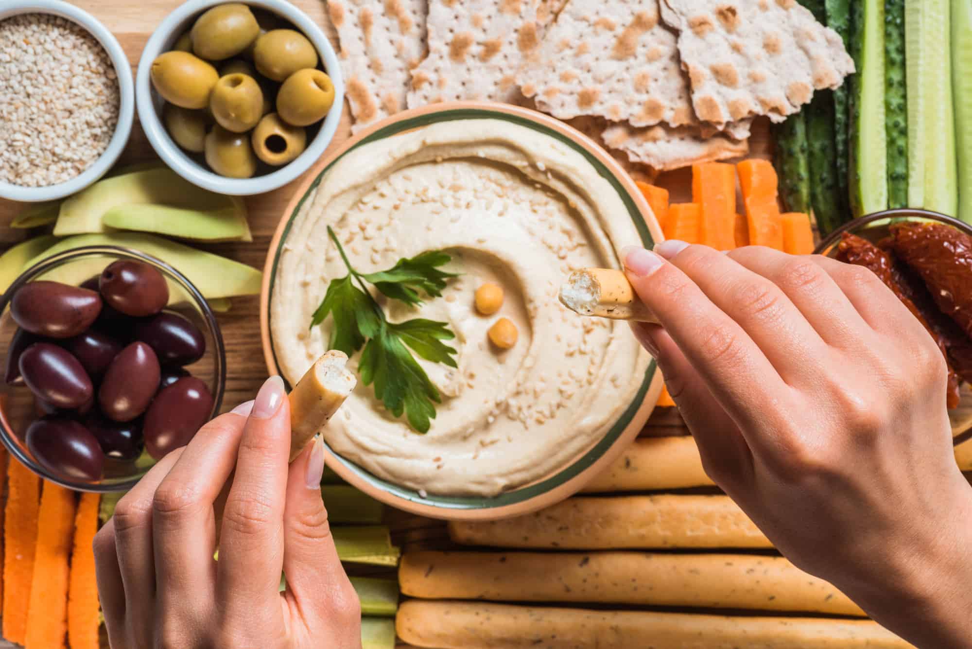 hummus on a table with olives, carrots, and grapes