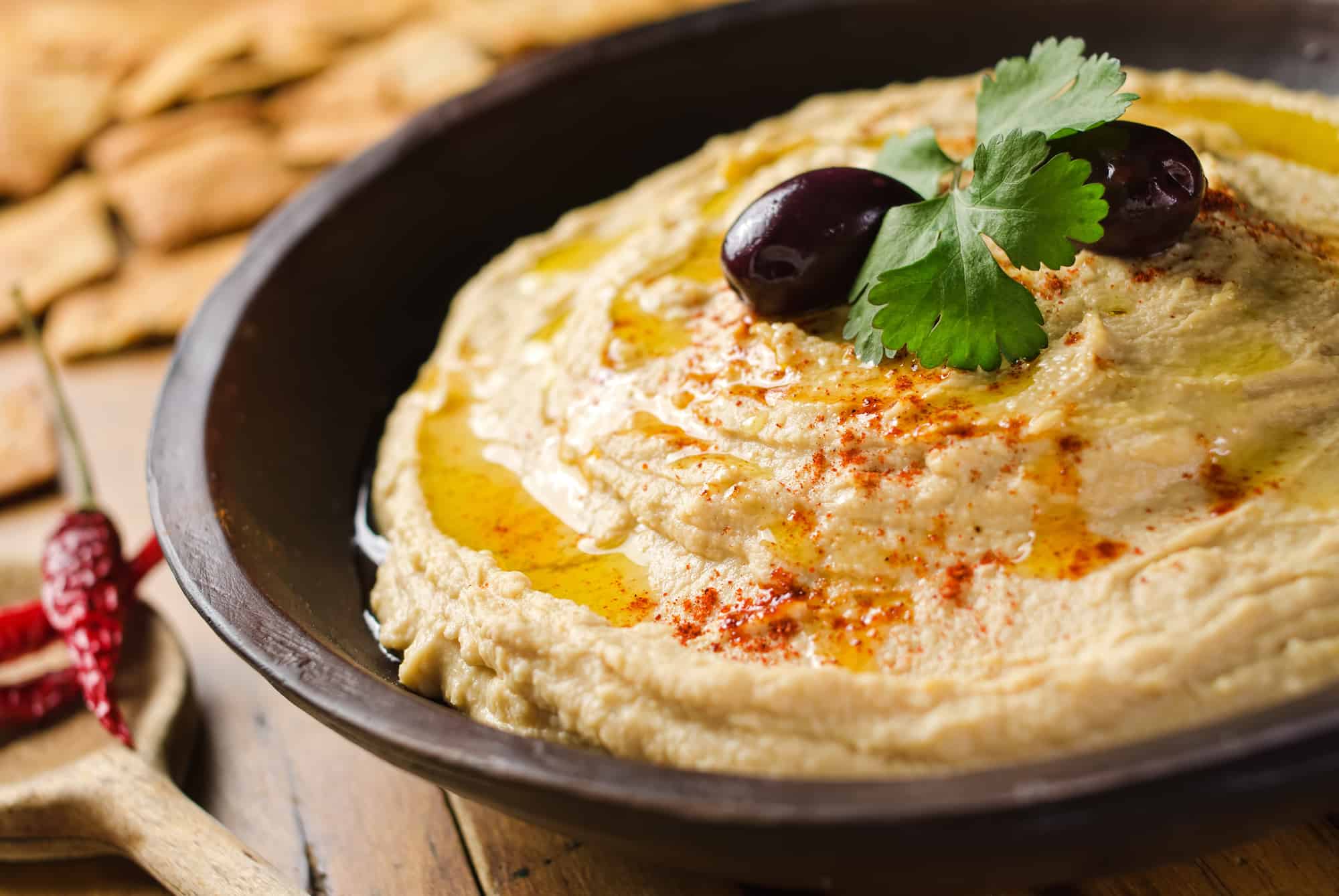 A bowl of creamy hummus with olive oil and pita chips