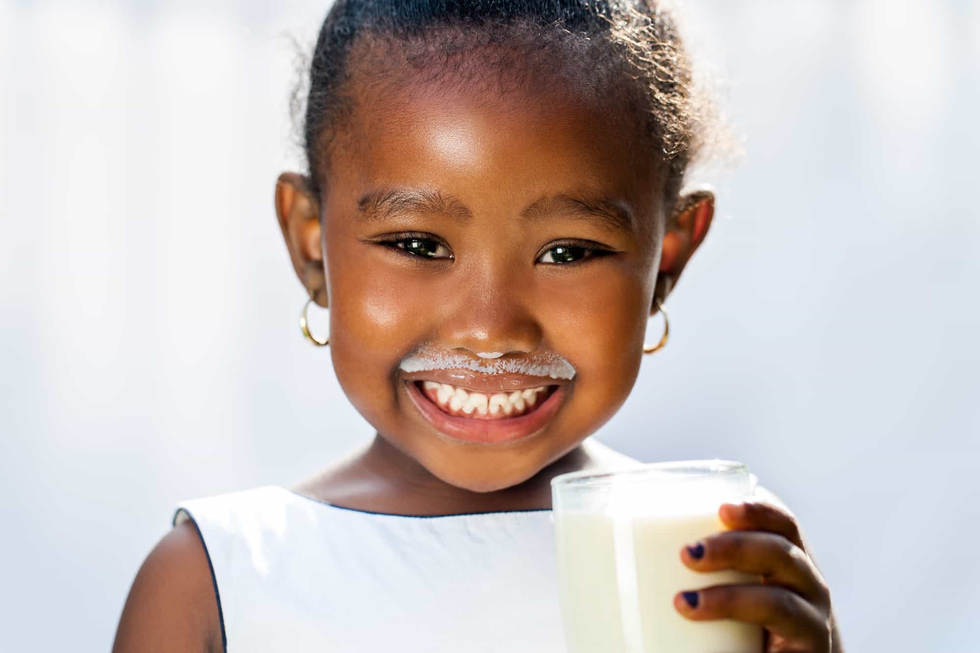 Close up fun portrait of cute black girl showing white milk mustache