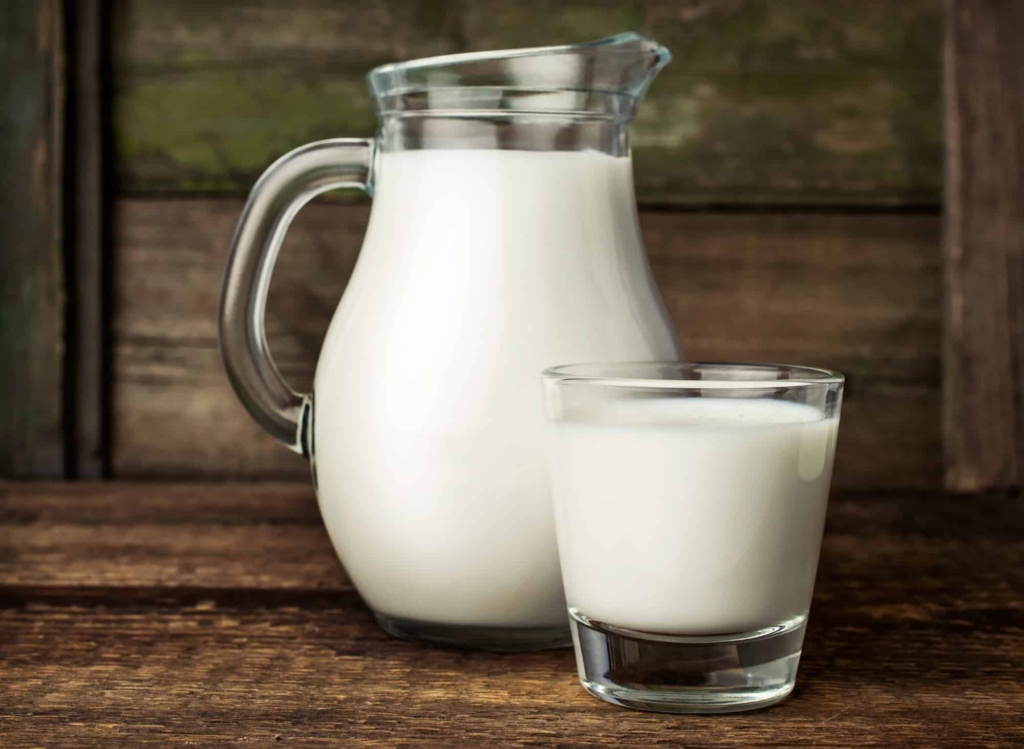 fresh milk in glass jug and glass on wooden background