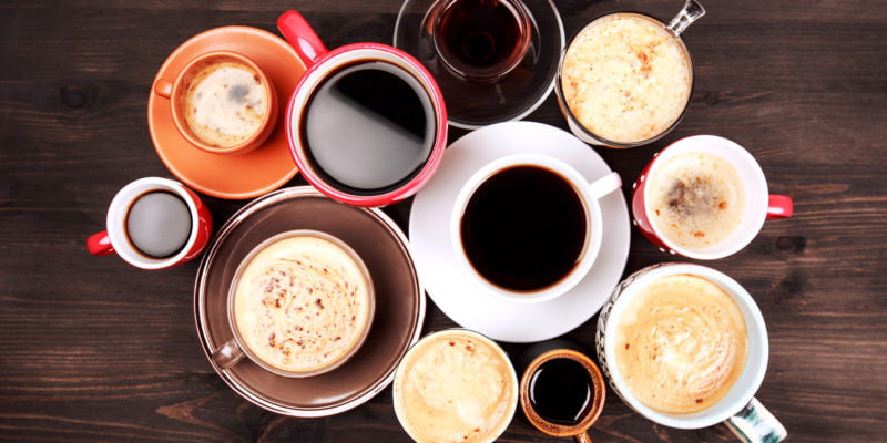 Many different cups of coffee on dark wooden table