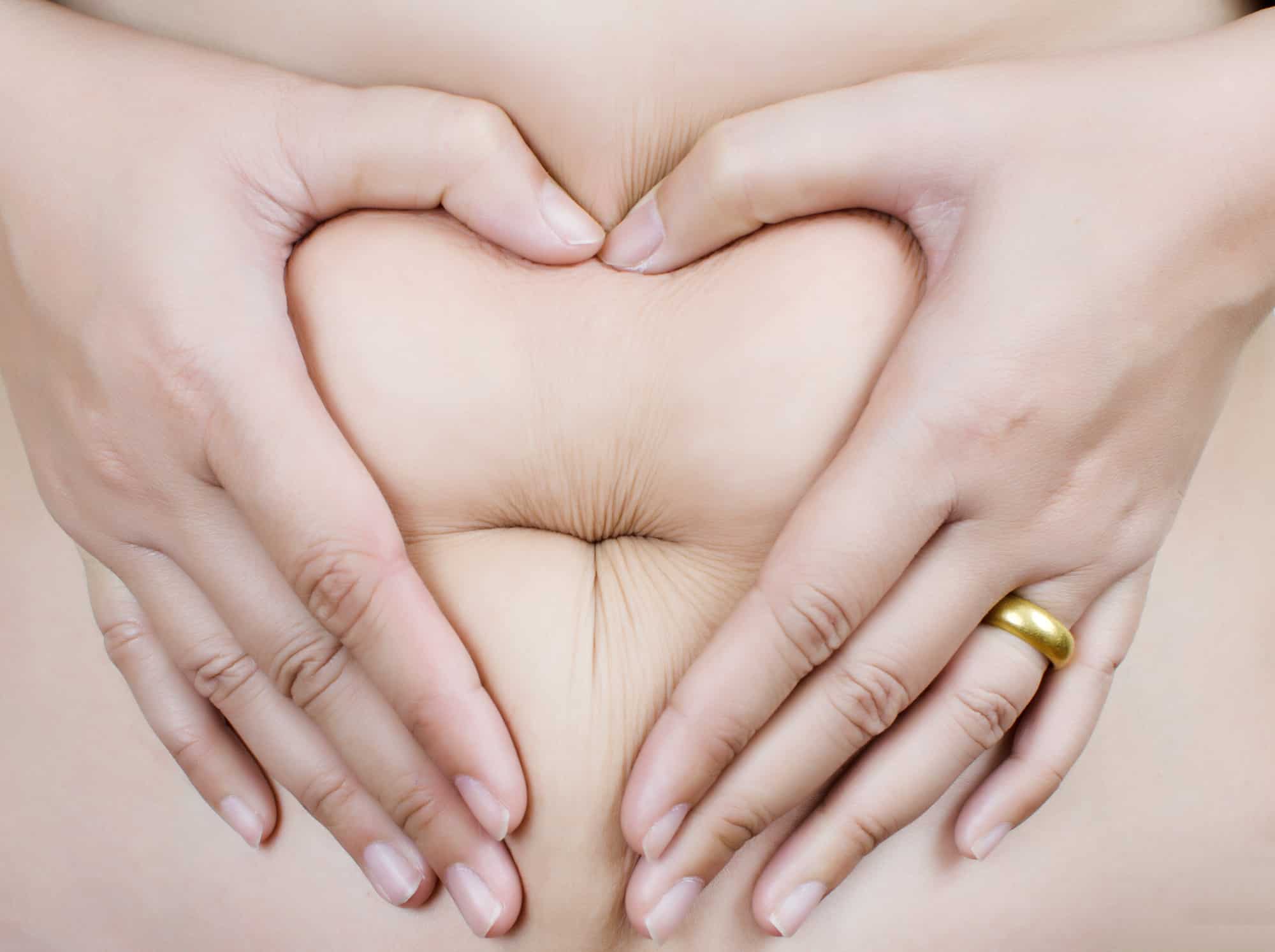 woman holding belly in a heart