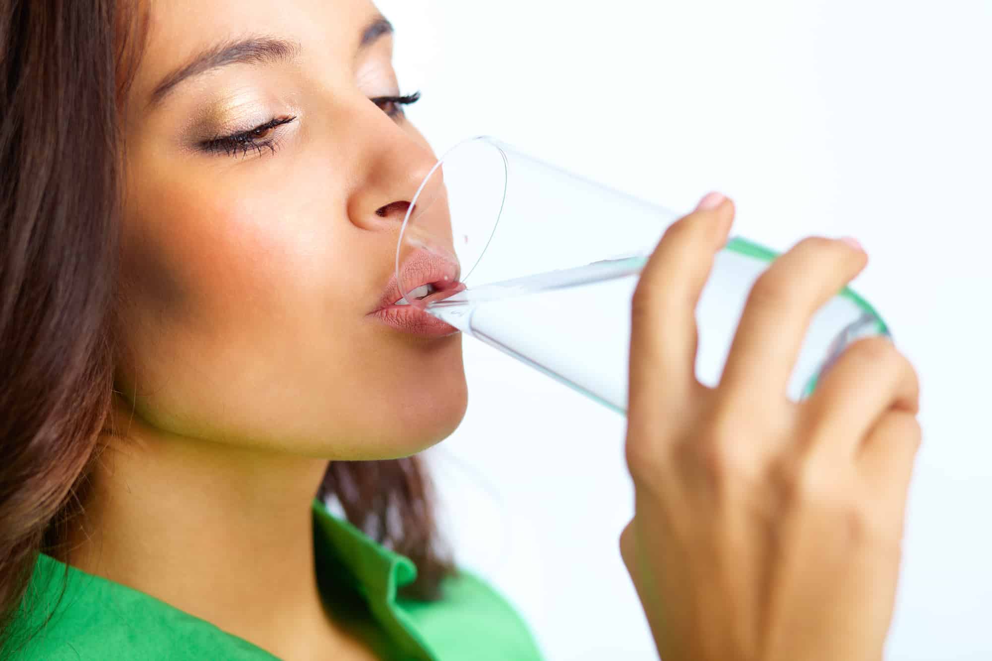 Close-up of pretty girl drinking water from glass