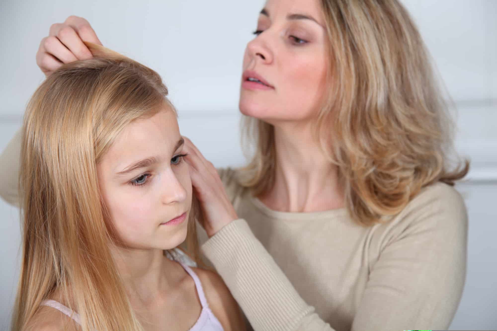Mother treating daughter's hair against lice