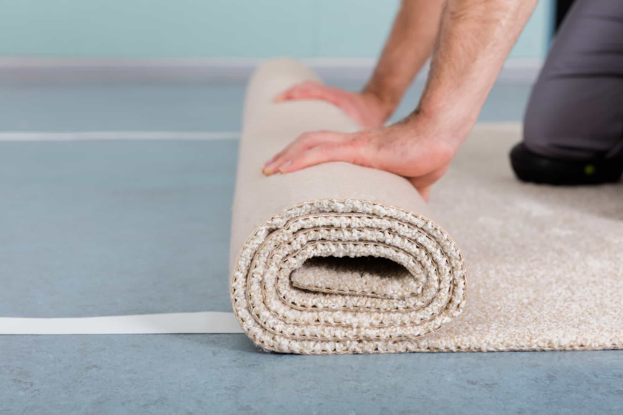 Close-up Of Worker's Hands Rolling Carpet At Home