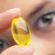 A woman holding a yellow vitamin capsule