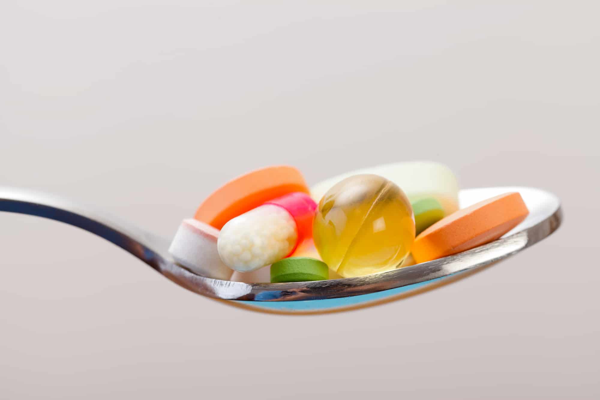 Various drugs vitamins and nutrition supplements on spoon.