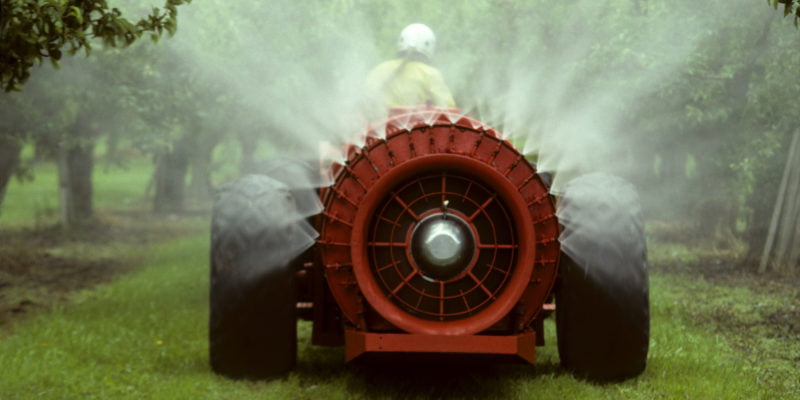 Red sprayer spraying an apple orchard