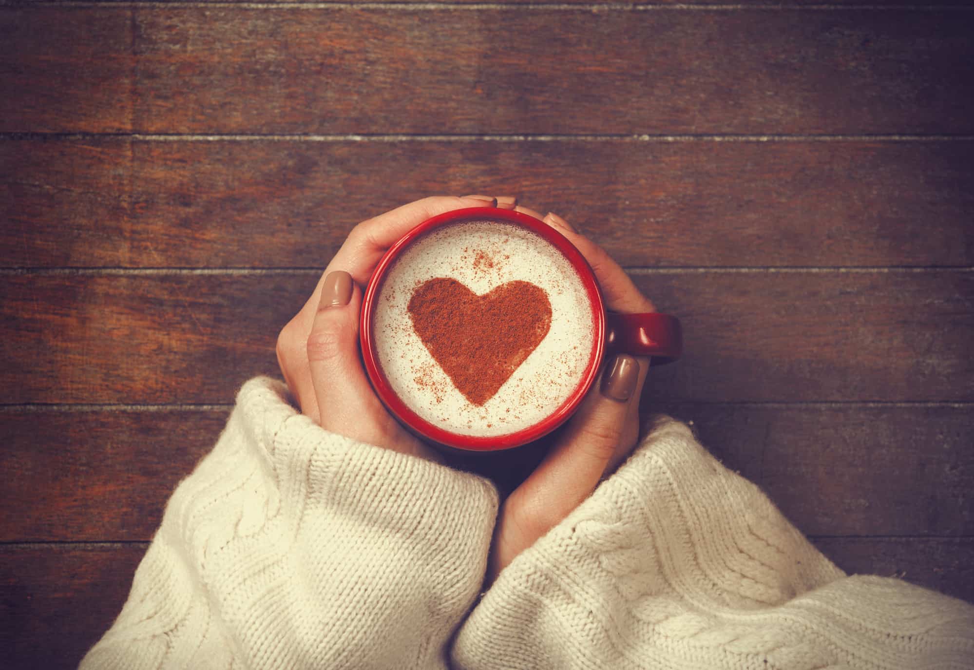 woman holding hot cup of coffee, with heart shape