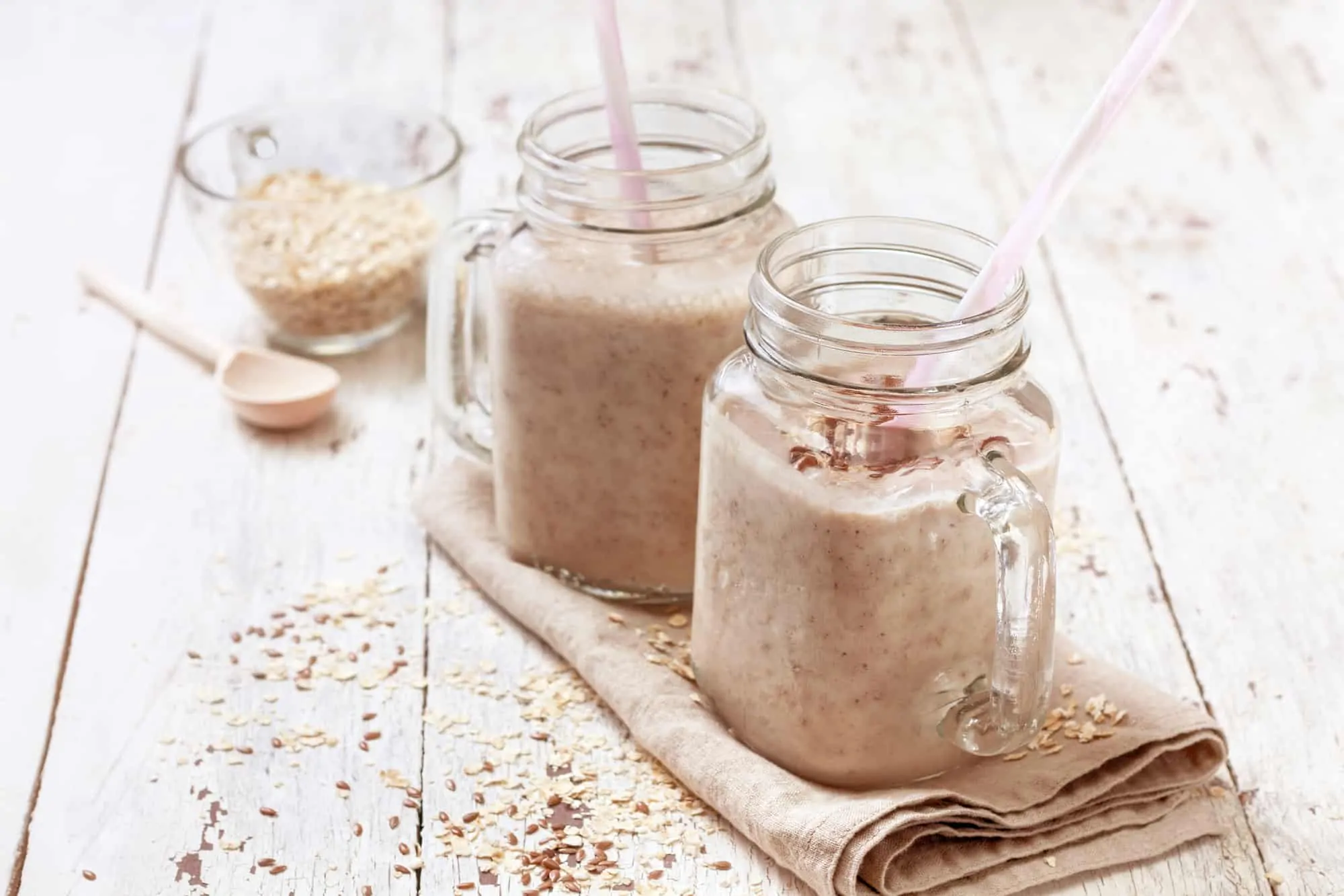 smoothies with oatmeal, flax seeds in glass jars on a wooden background