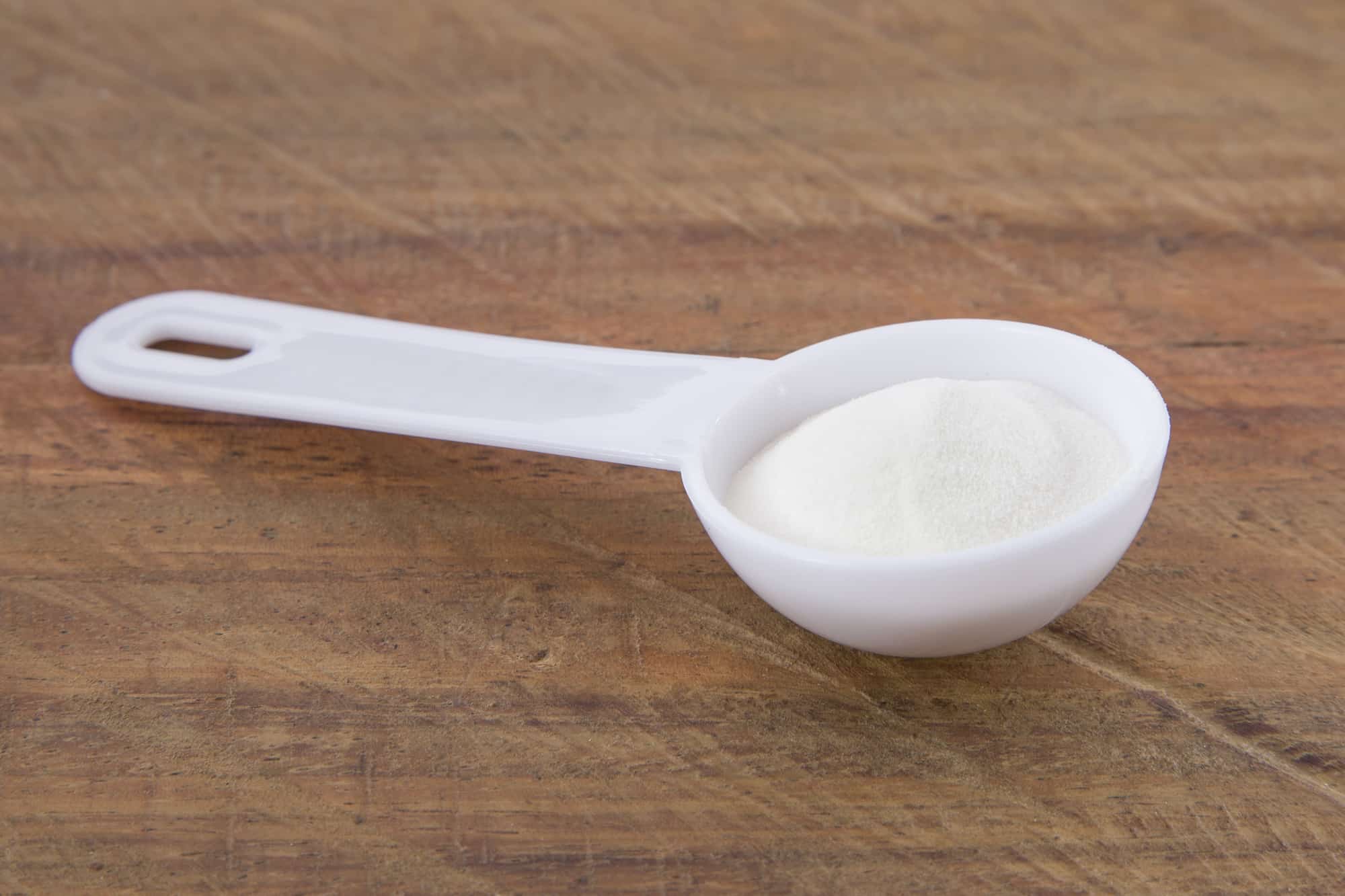 grassfed Collagen in a white plastic spoon on the table