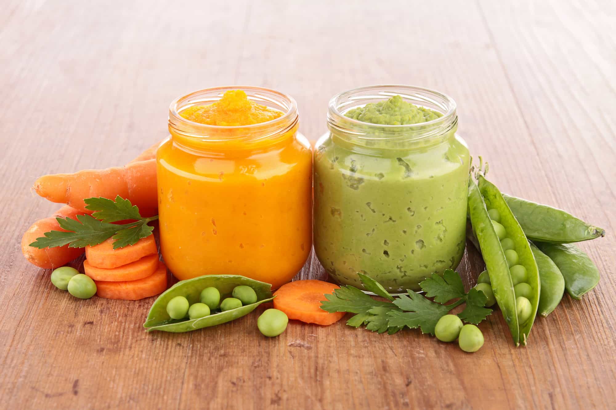 peas and carrots baby food on the wood table