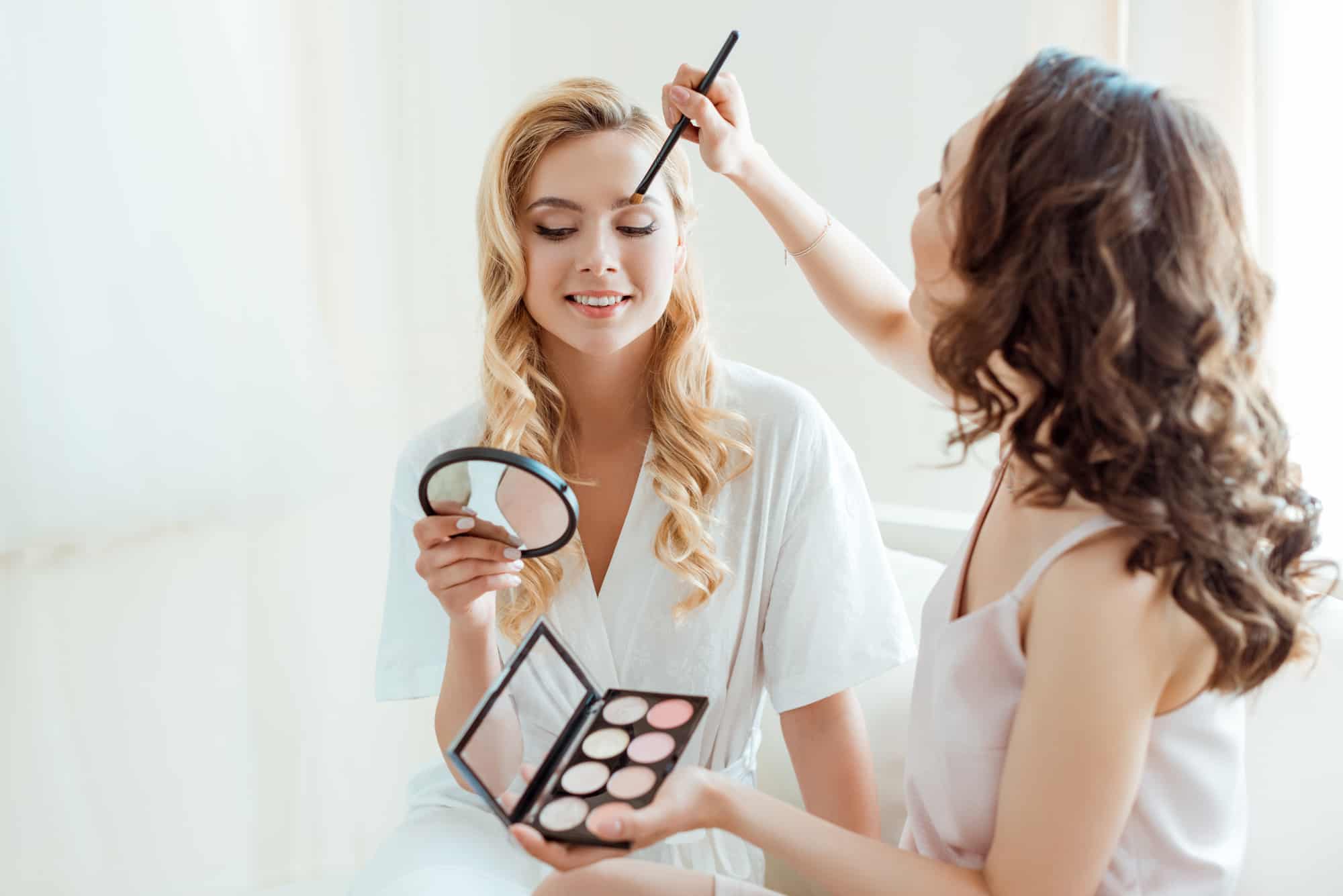 blonde woman having natural makeup applied 