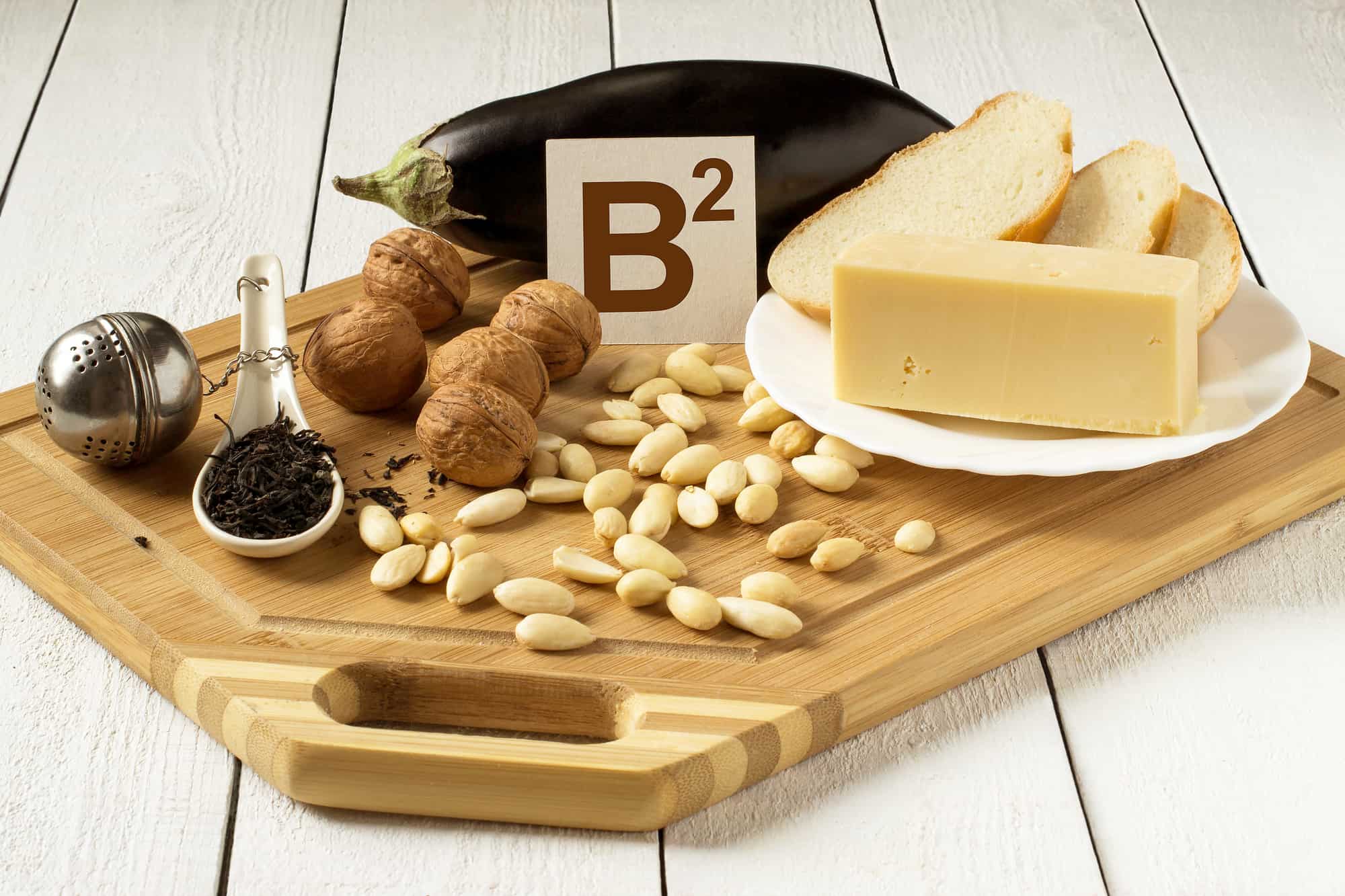 Foods rich in vitamin B2: eggplant, cheese, white bread, walnuts, almonds, tea on a cutting board