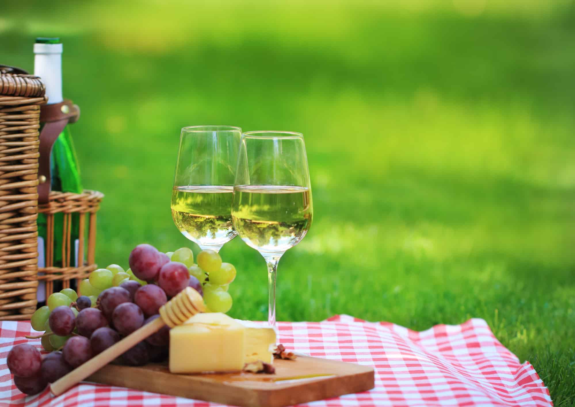 Various sorts of cheese, grapes and two glasses of the white wine