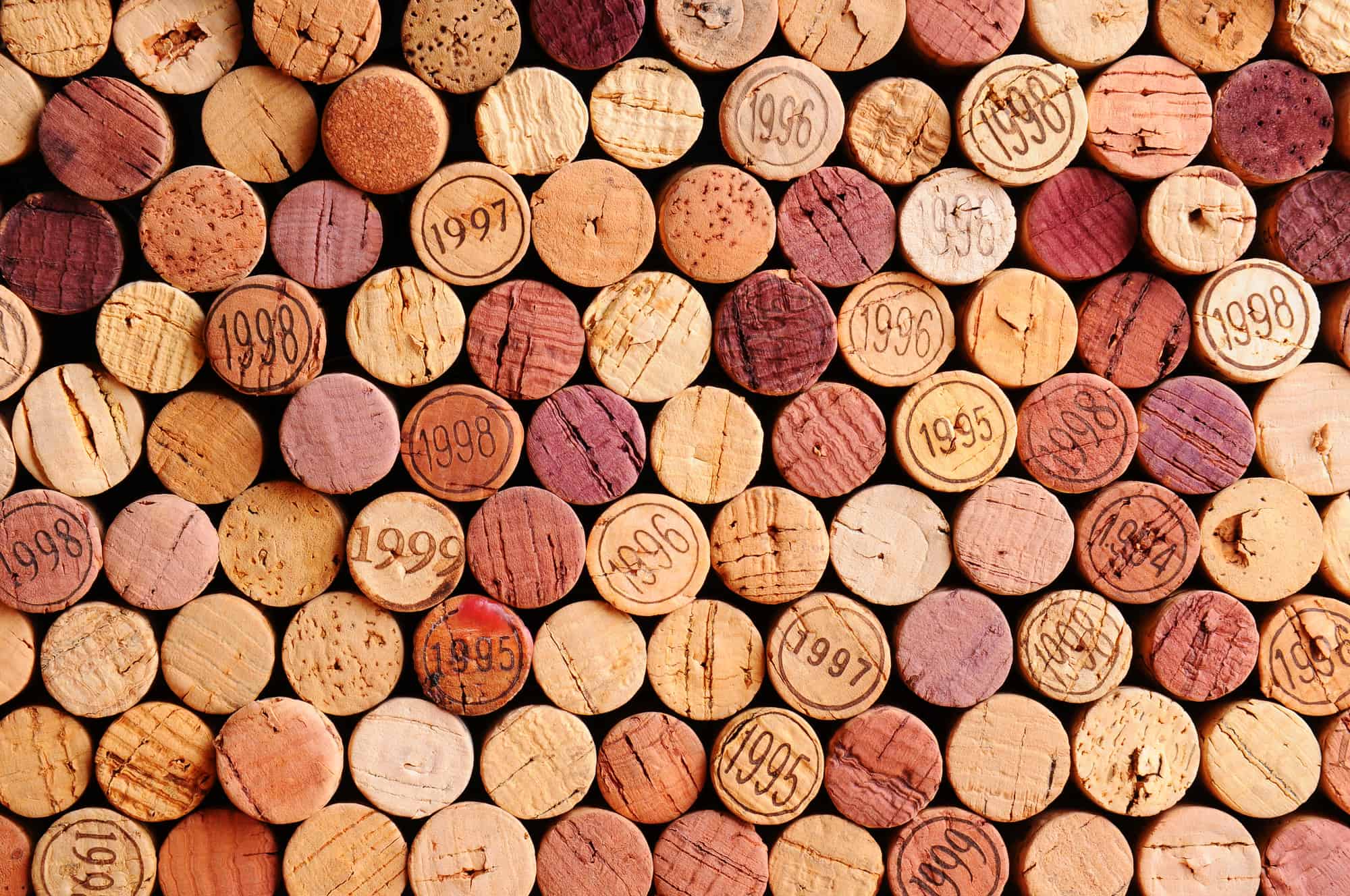 Closeup of a wall of used wine corks. A random selection of use wine corks, some with vintage years. Horizontal format that fills the frame