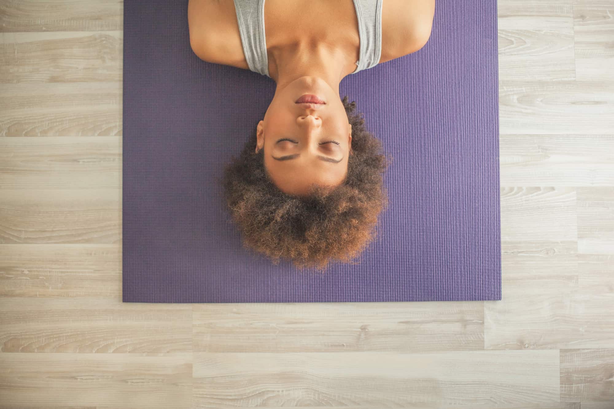 Indoor high-angle shot of woman lying on a yoga mat with her eyes closed