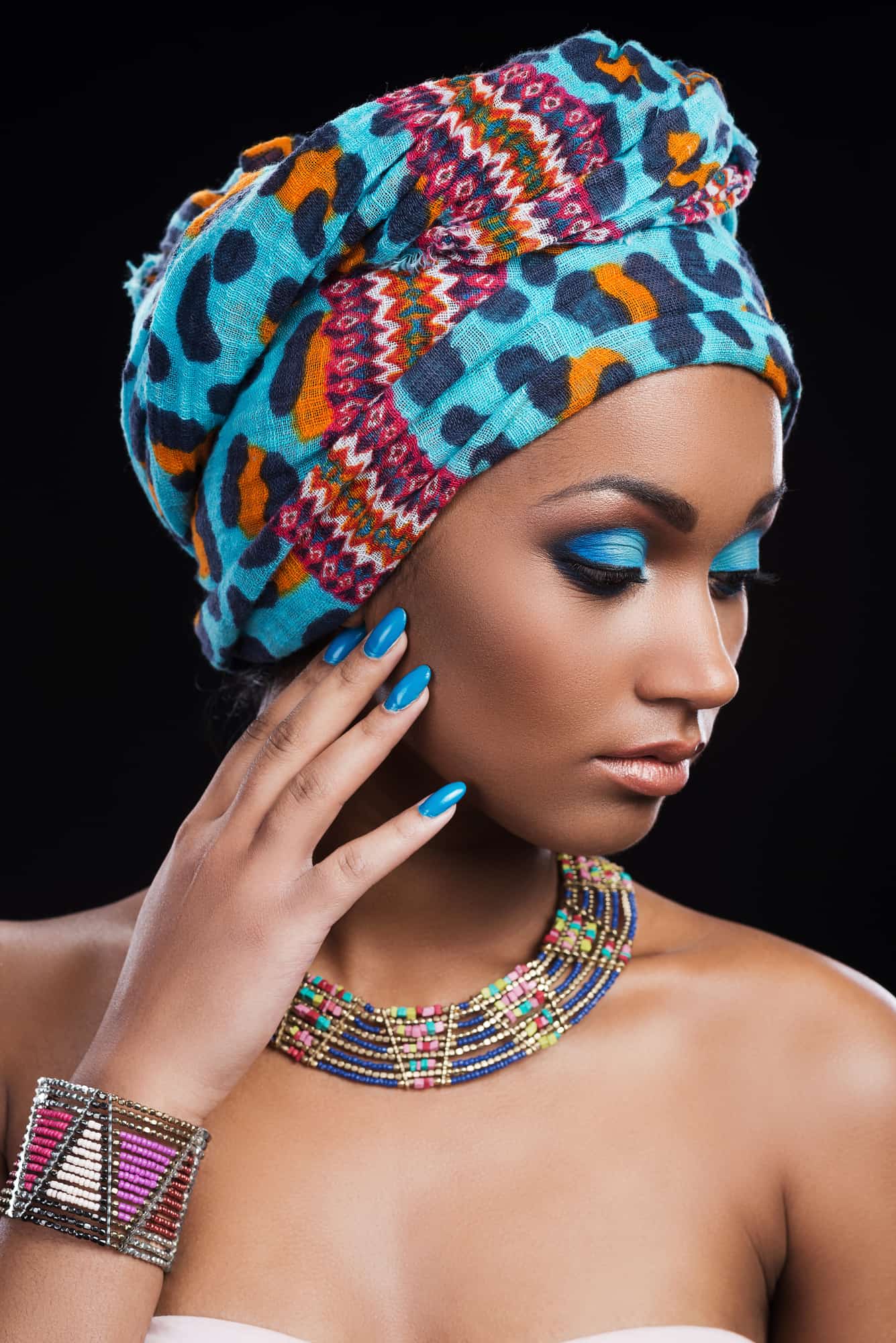 Confident in her perfect look. Beautiful African woman wearing a headscarf and necklace looking away and touching her face