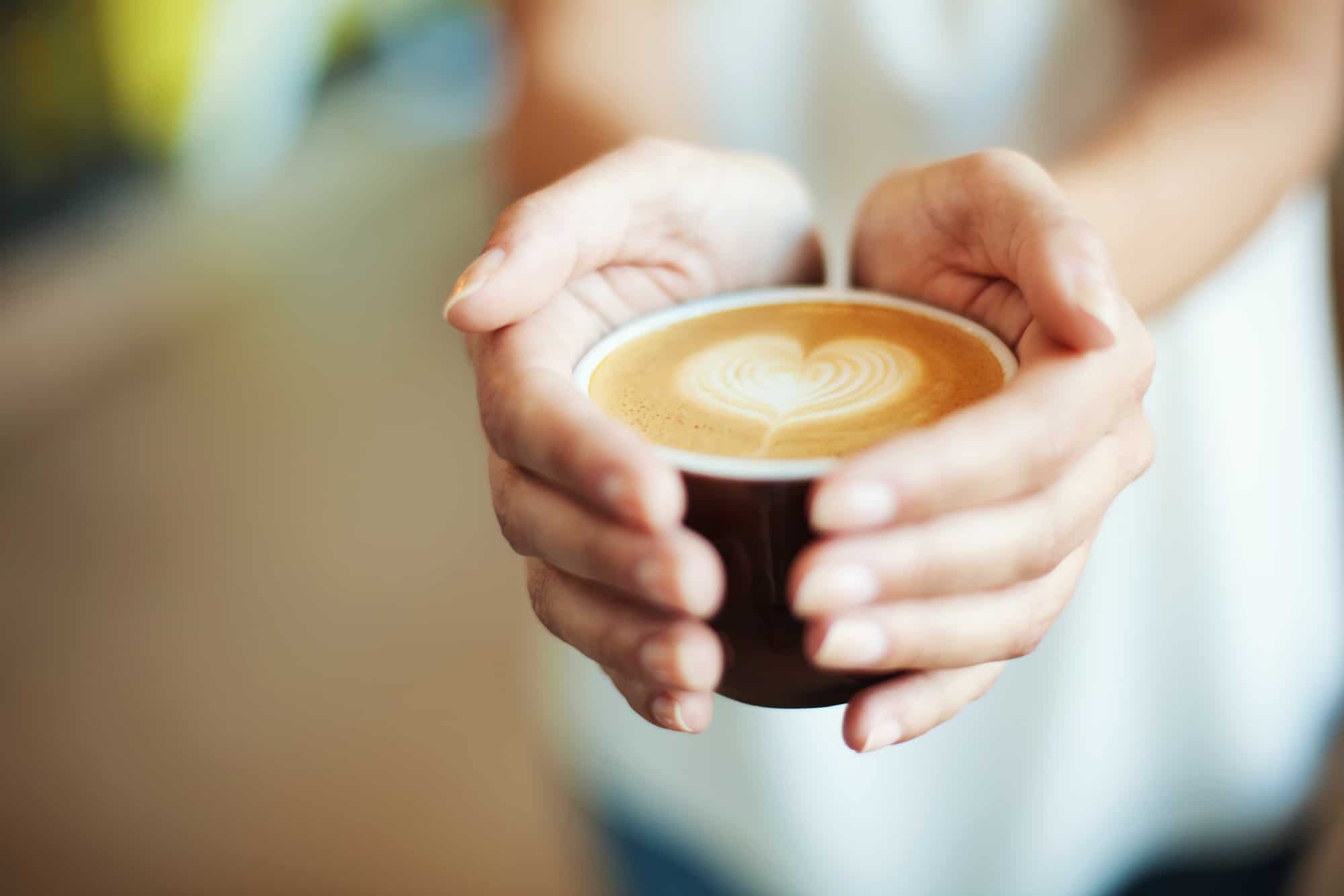 Closeup of Female holding coffee with heart symbol