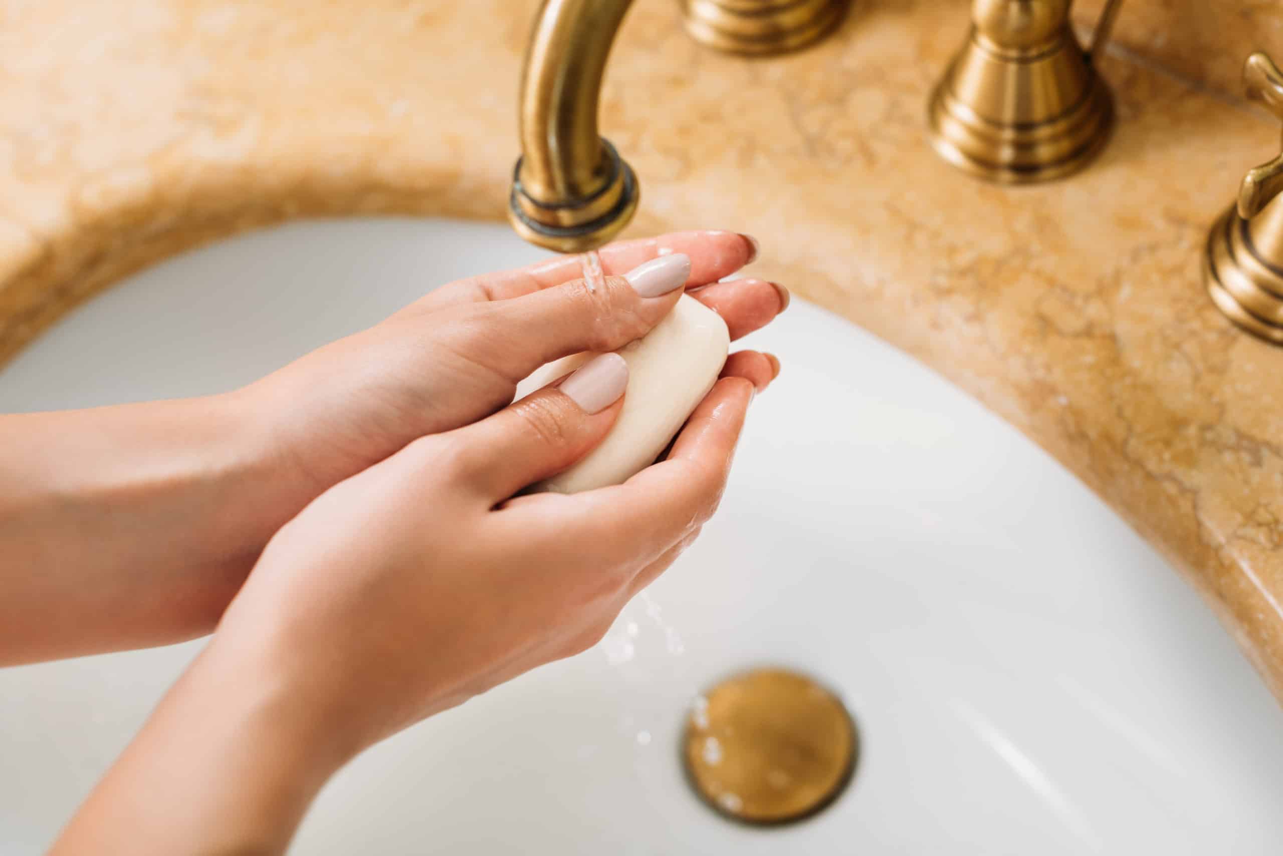 Woman washing hands with soap in the bathroom