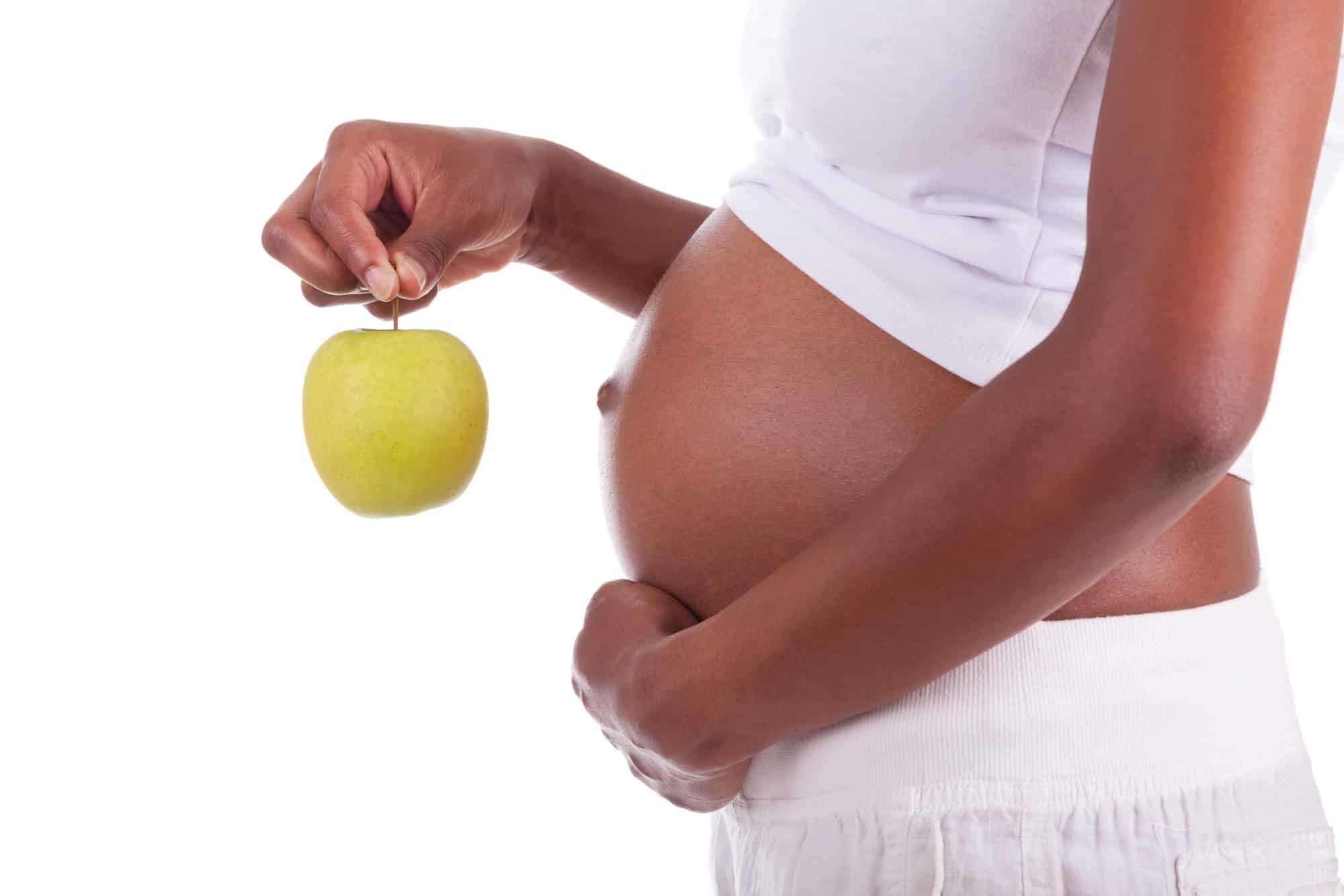 Young pregnant black woman holding a green apple, isolated on white background