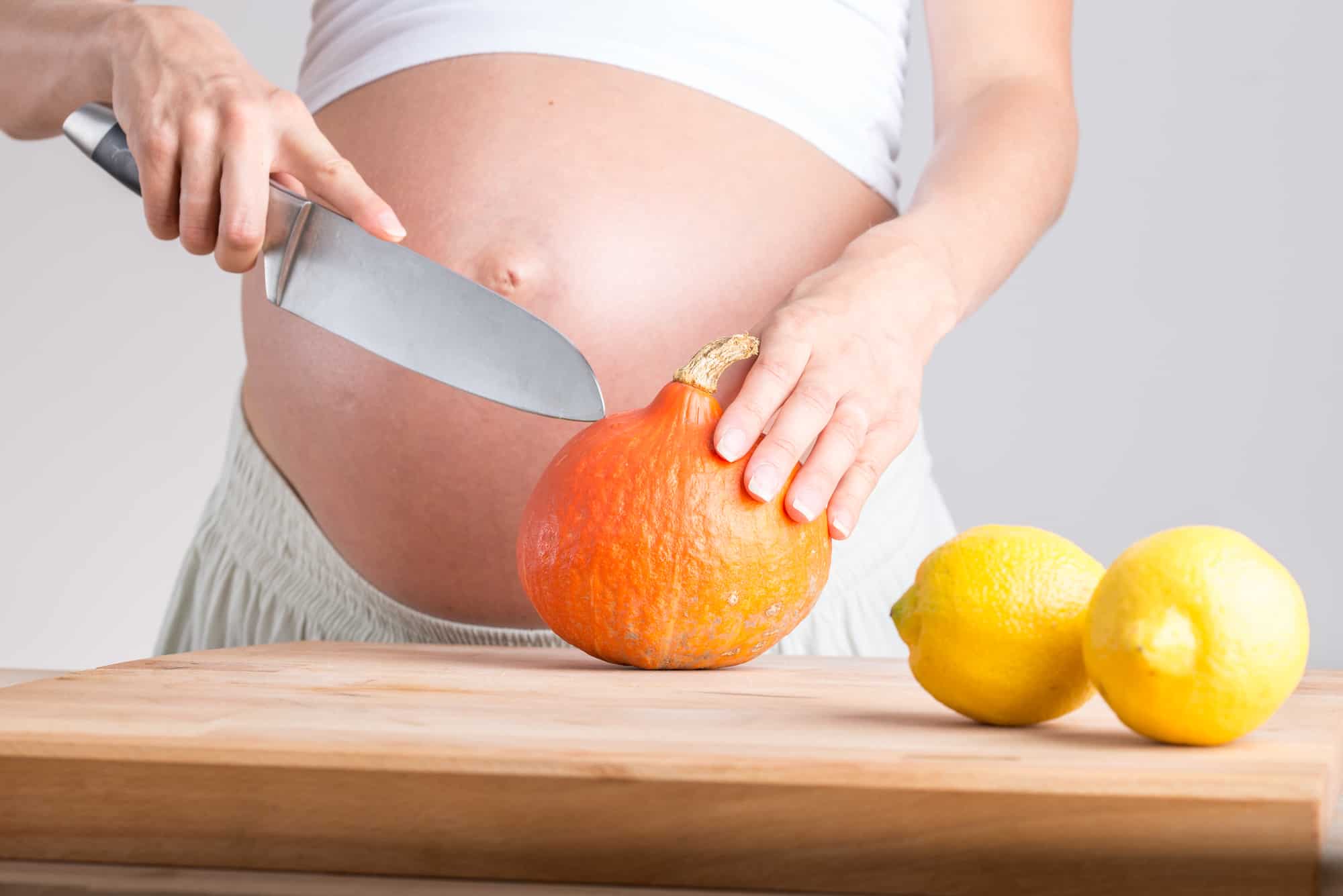 Pregnant woman slicing an organic tangelo