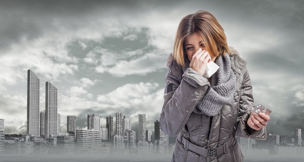 beautiful young woman sneezing and holding medicines