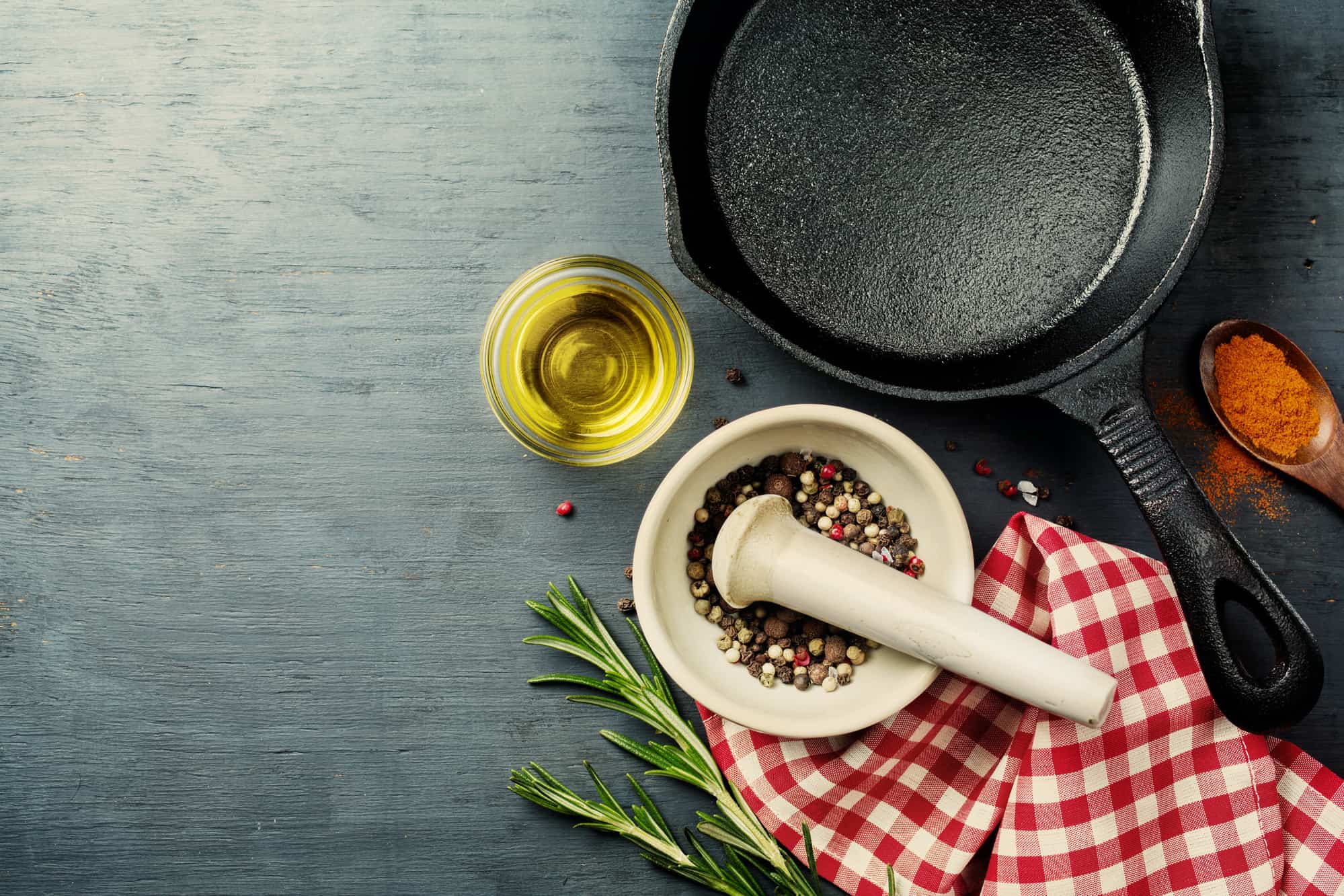 food background with cast iron skillet, herbs and spices selection