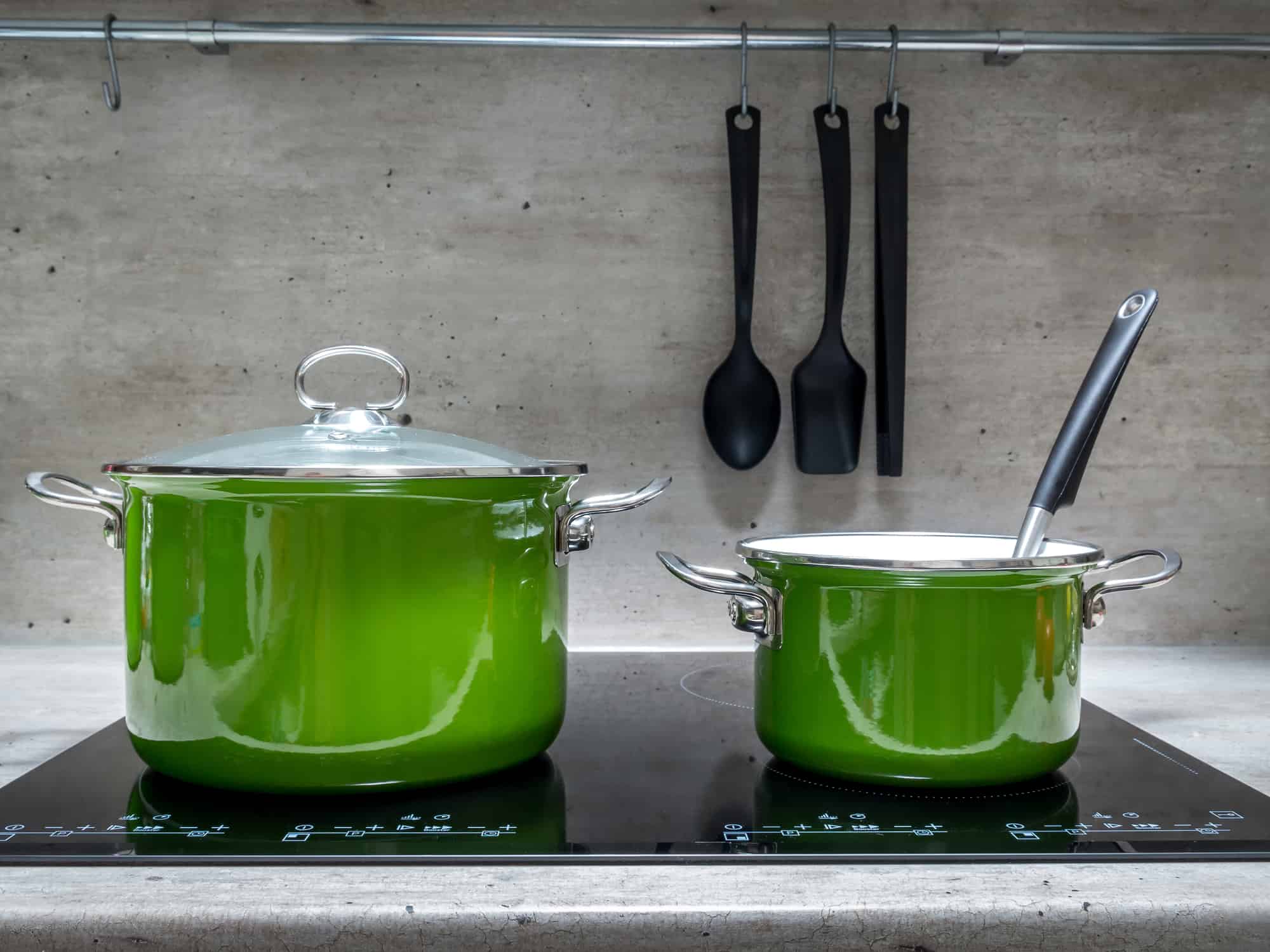 Two green enamel stewpots on black induction cooker