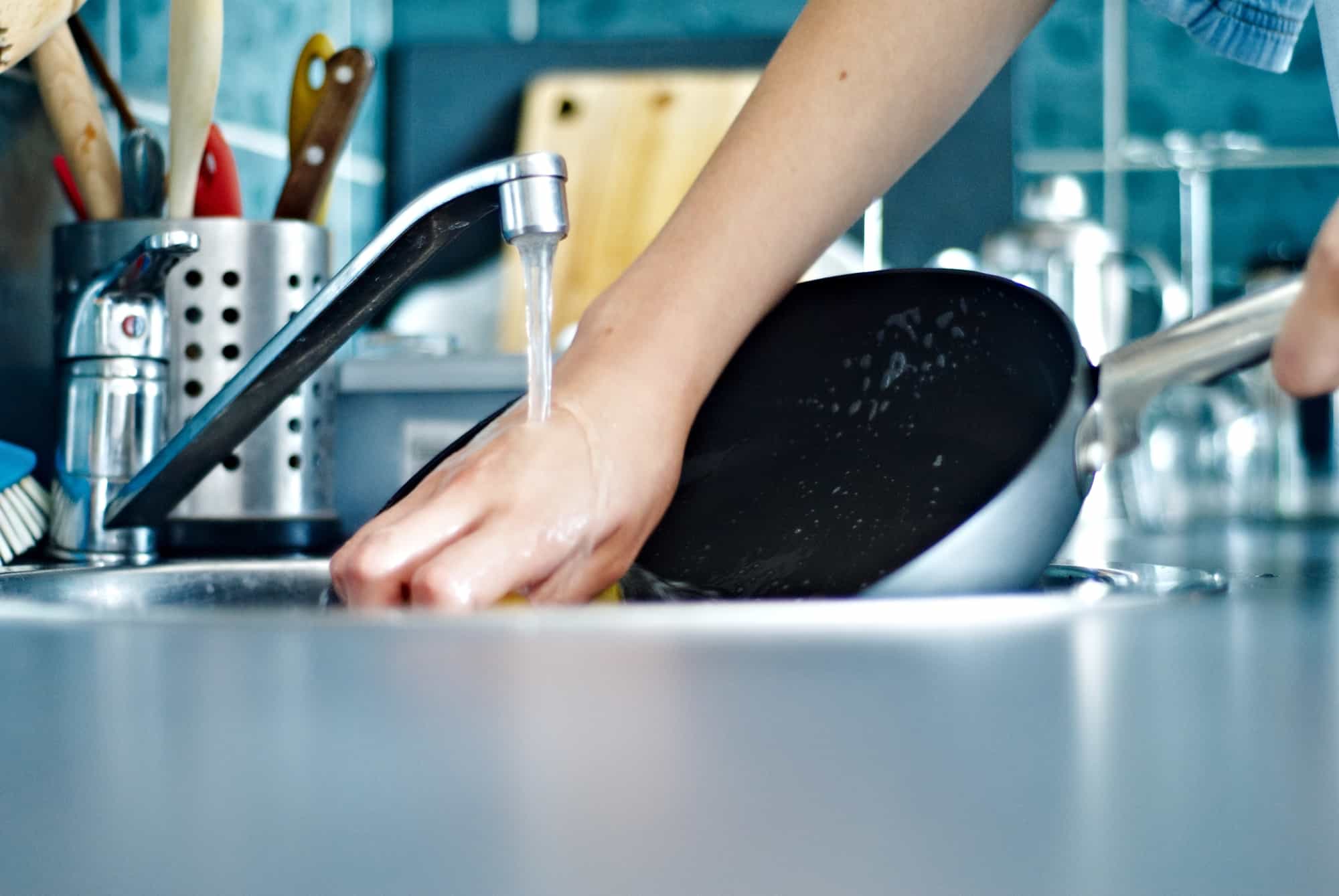 woman washing ceramic pan with non-toxic dish soap