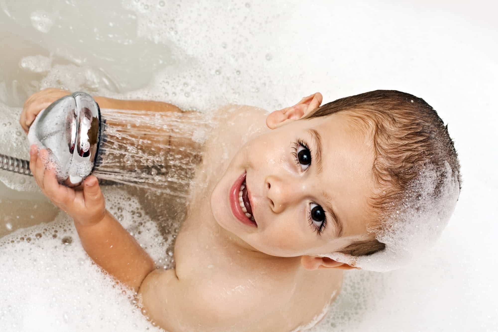 Boy playing with shower head filter