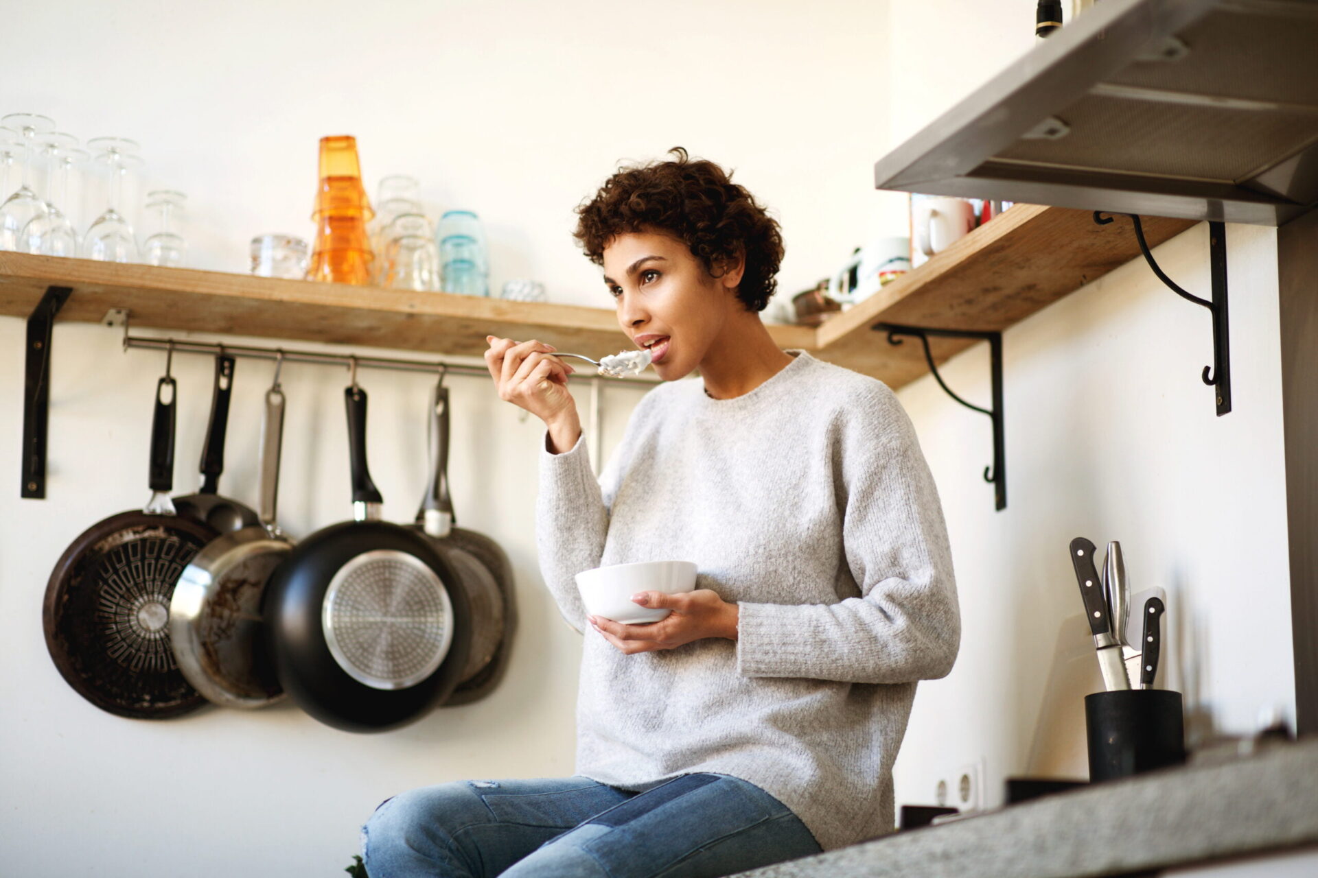 woman sitting on kitchen counter eating yogurt