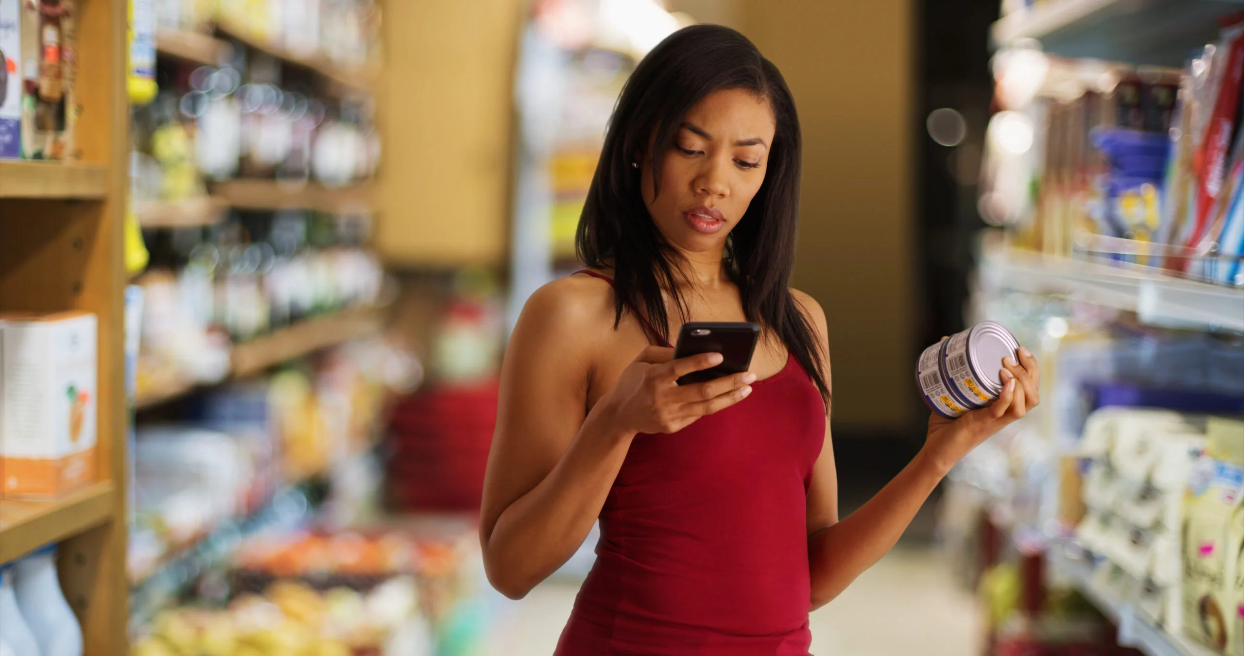 Black woman studies her phone at the grocery store