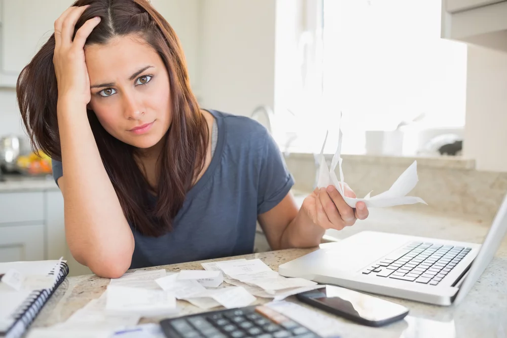 Young woman looking worried over finances in kitchen