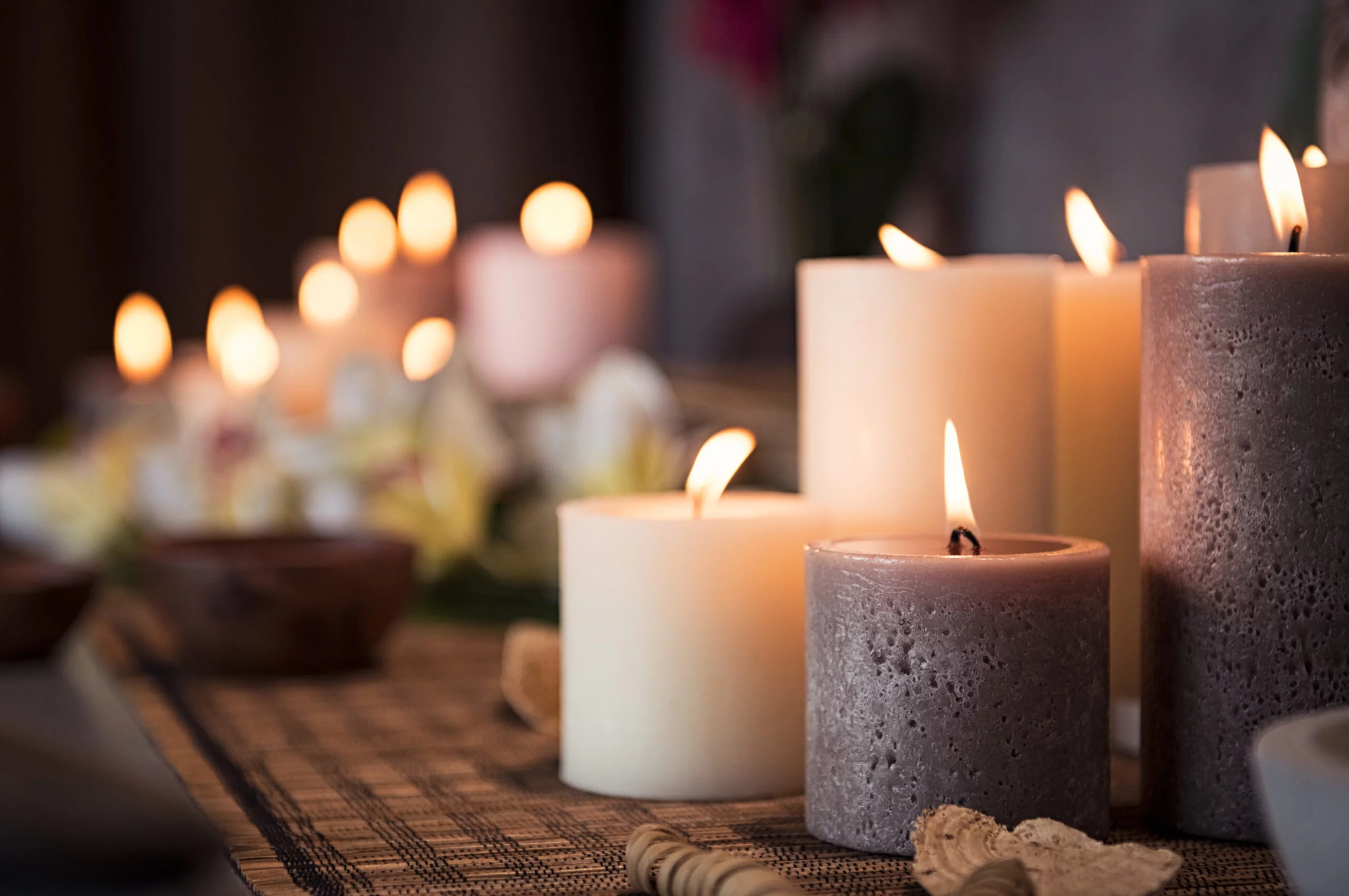 Closeup of burning candles spreading aroma on table in a spa room. Beautiful composition with grey and white candles for spa treatment