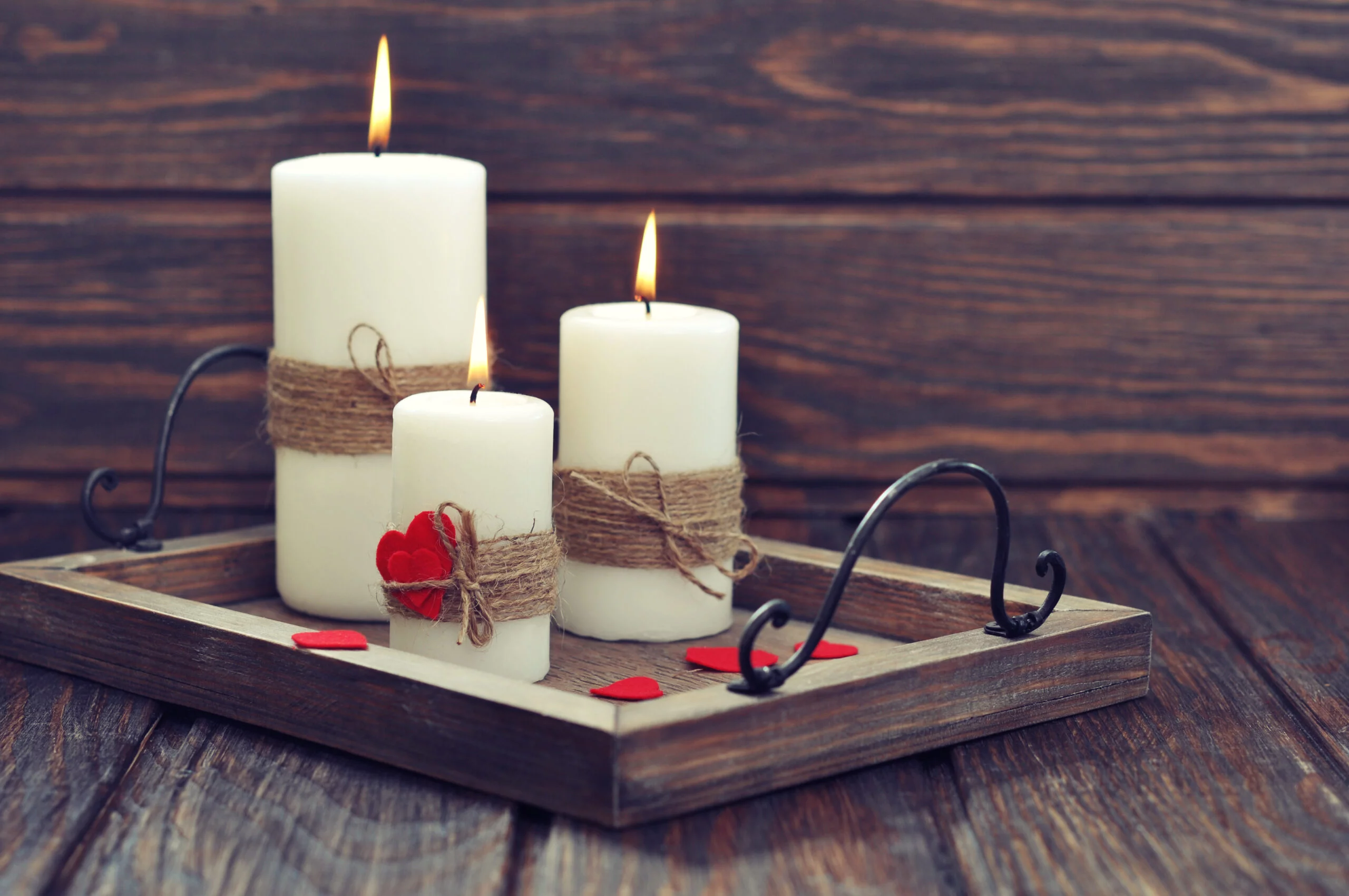 Candles on vintage tray with fabric hearts on wooden 