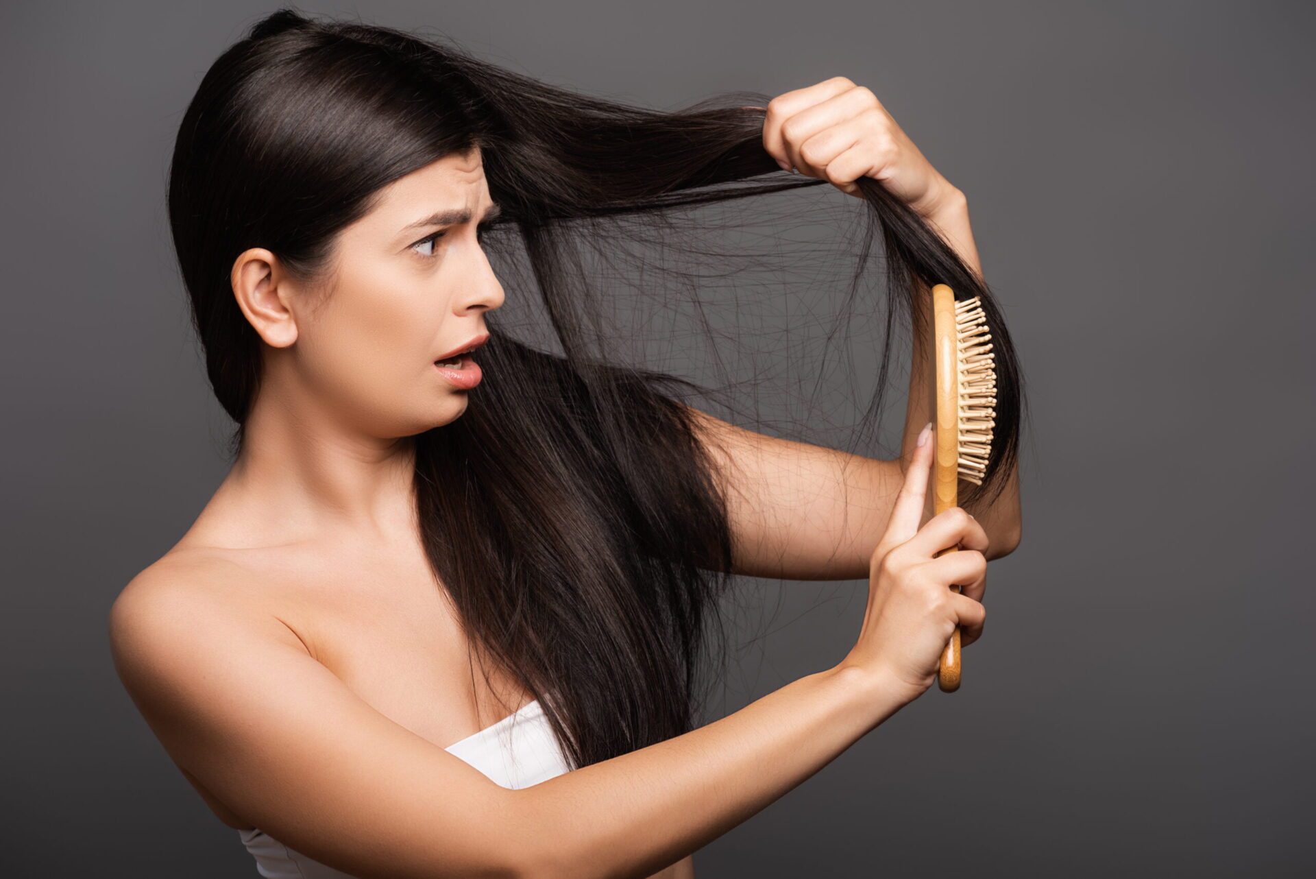 Latino woman looking at her oily hair that needs dry shampoo