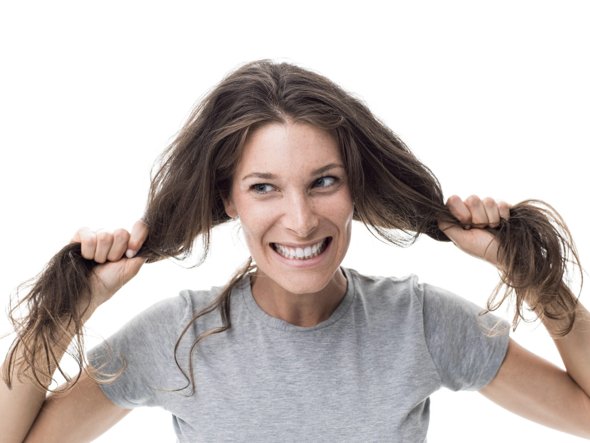 Angry woman having a bad hair day, she is pulling her messy and tangled hair